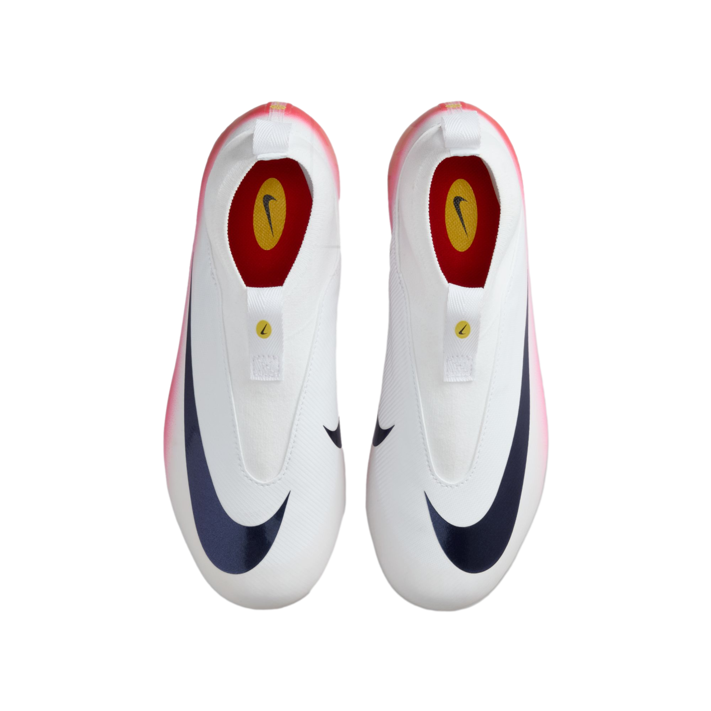 Top-down view of white, laceless Nike soccer cleats with a large navy swoosh and pink-to-white gradient heels on a black background.