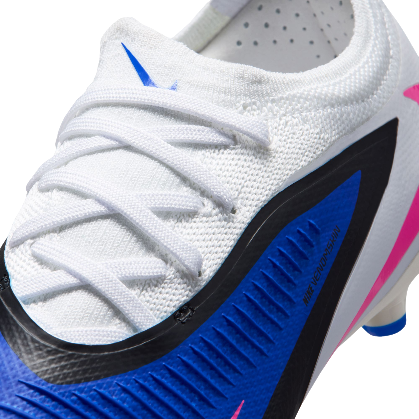 Close-up of a white Nike soccer cleat featuring a blue and black panel with "NIKE VENOMSKIN" branding, white laces, and pink accents.
