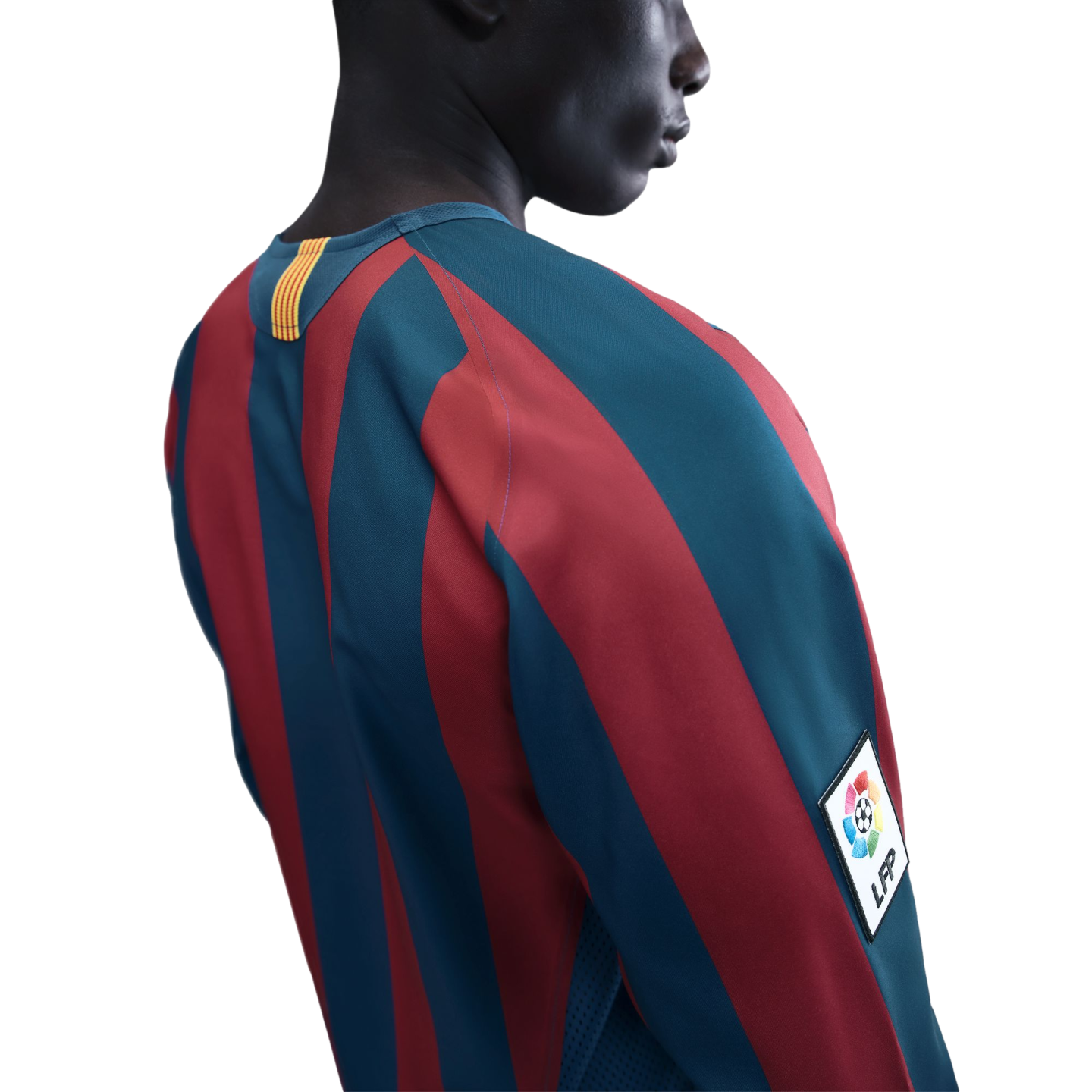 A close-up profile view of a person against a black background, wearing a red and blue vertically striped long-sleeved soccer jersey with an LFP patch on the sleeve.