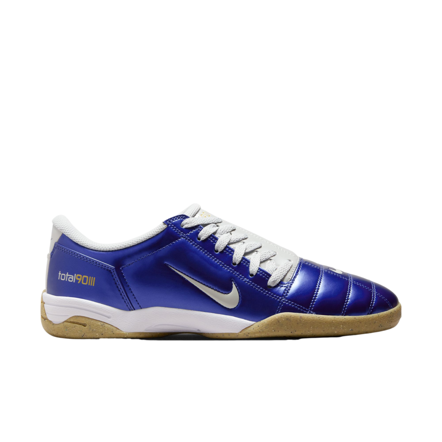Side view of a metallic blue Nike Total 90 III indoor soccer shoe with white laces, a silver swoosh, and a gum outsole, set against a black background.