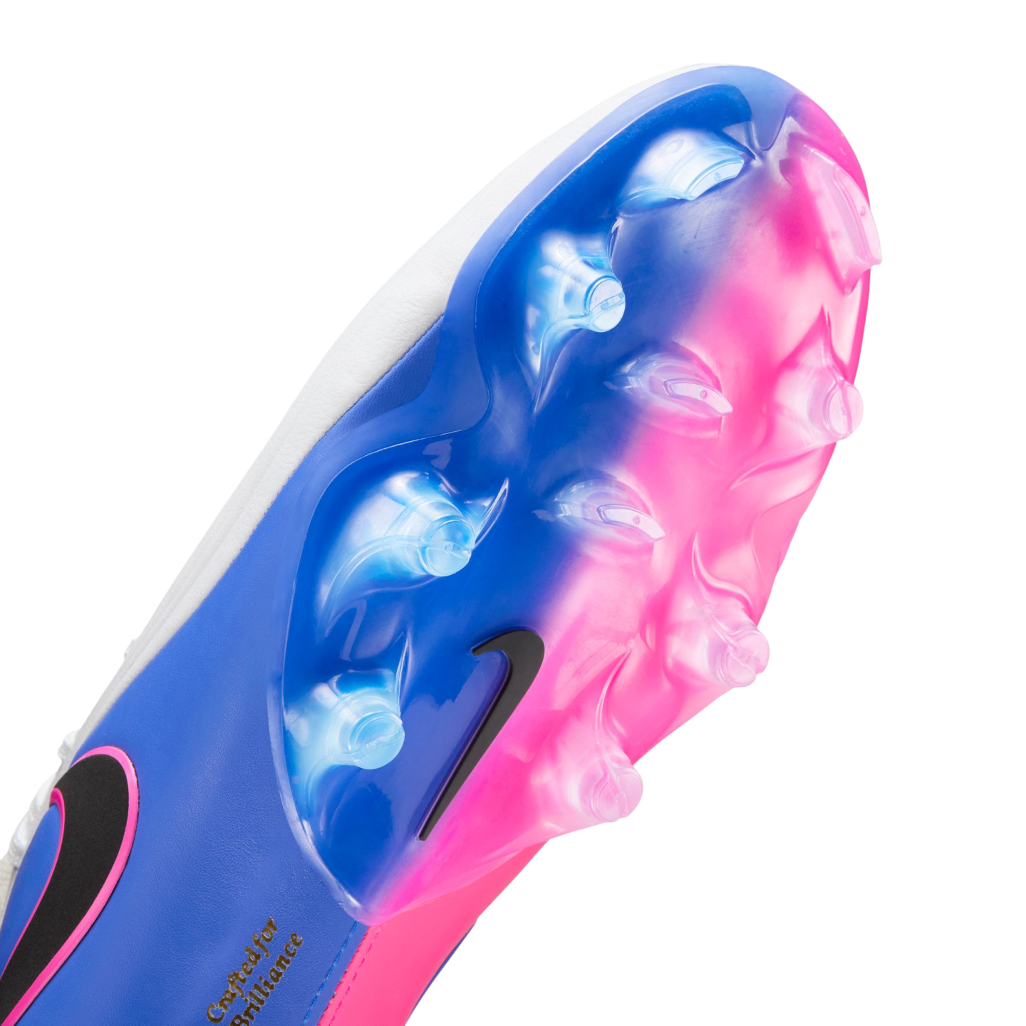 Close-up bottom view of a Nike soccer cleat featuring a vibrant blue and pink gradient soleplate with clear studs and a small black swoosh.