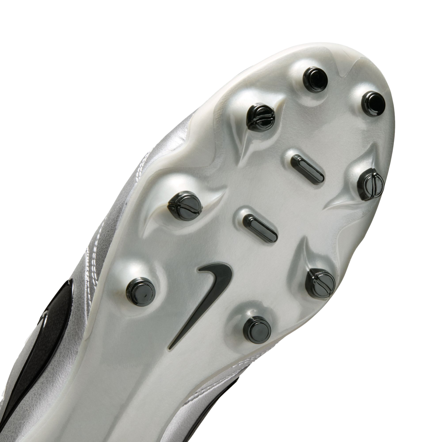 A close-up of the silver soleplate of a Nike soccer cleat, featuring black studs and a black Nike swoosh logo, set against a solid black background.