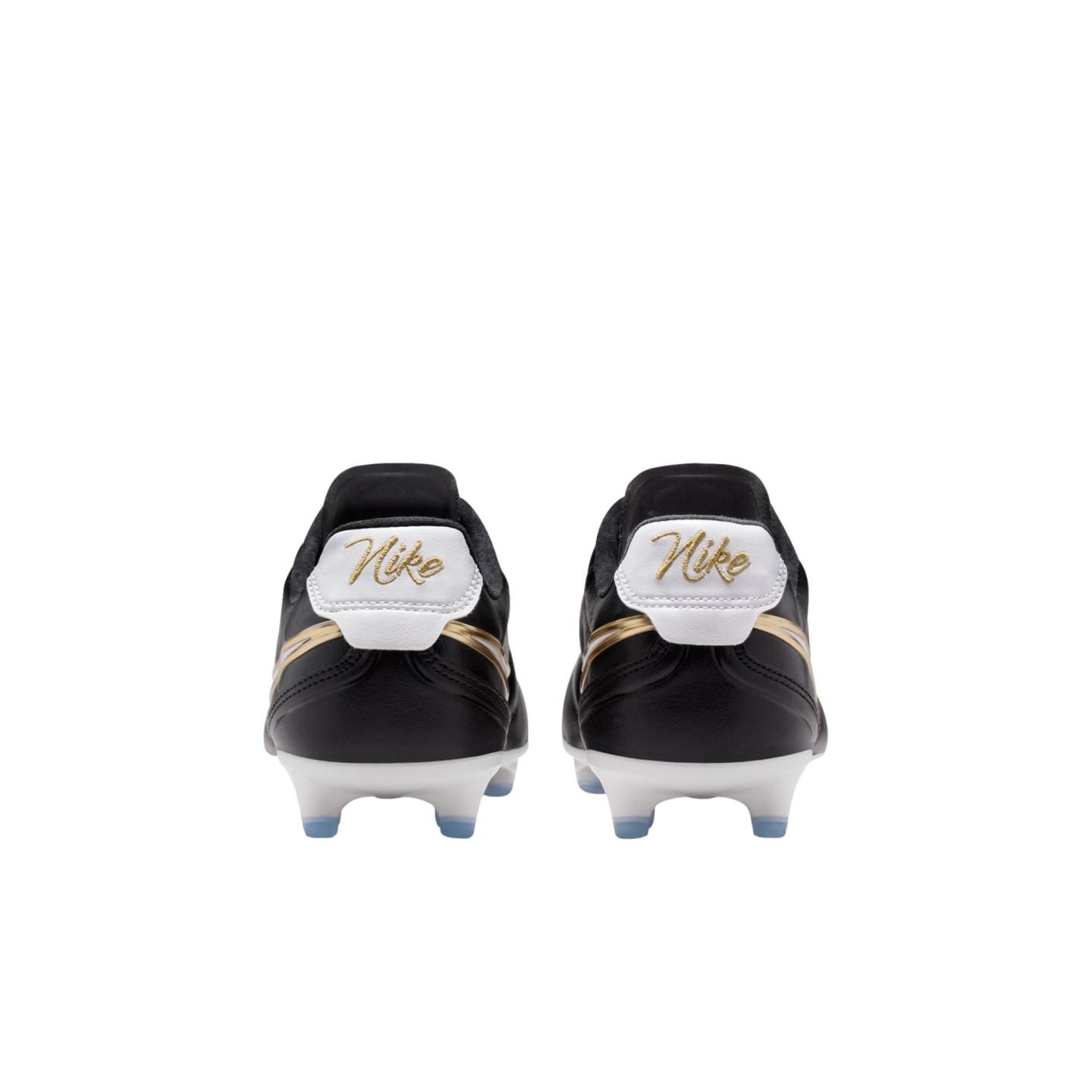 Rear view of black Nike soccer cleats with gold cursive branding on white heel tabs and white soleplates with blue studs against a black background.