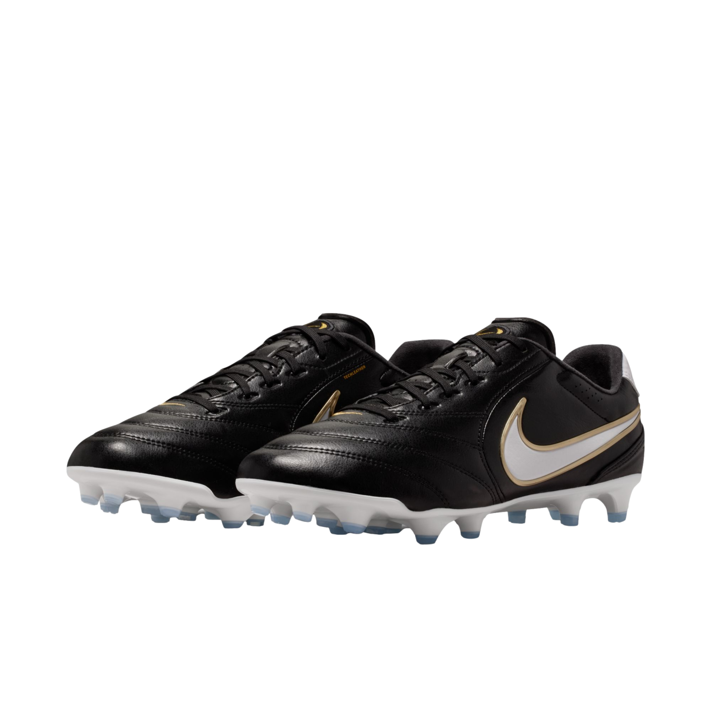 Black Nike leather soccer cleats with white and gold swooshes, featuring white soles and light blue studs, presented against a solid black background.
