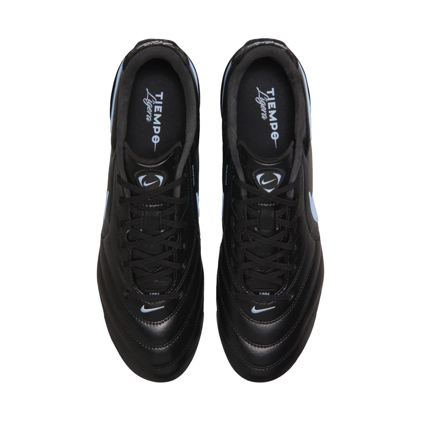 Top-down view of a pair of black Nike Tiempo Ligera soccer cleats with light blue swooshes, set against a solid black background.