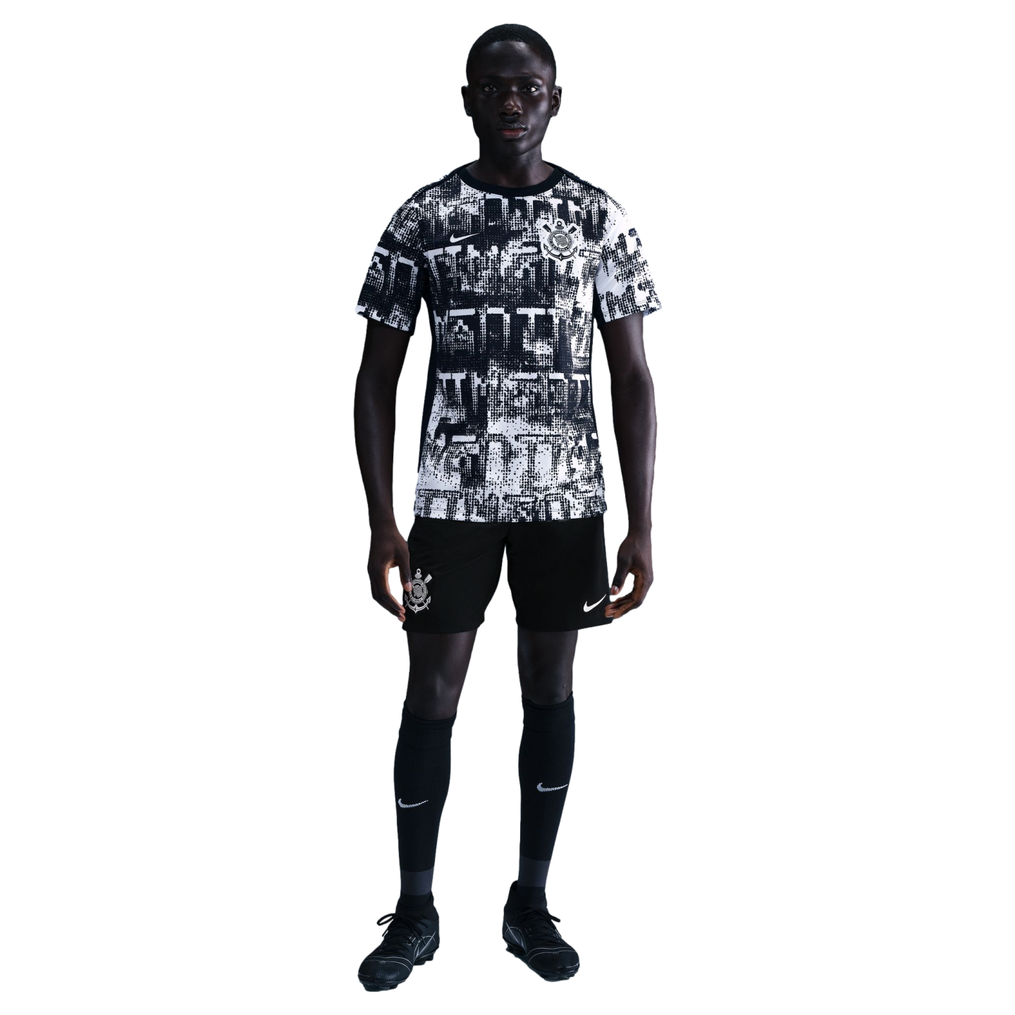 A man wearing a black and white graphic soccer kit with a Corinthians crest and Nike logo, standing against a black background.