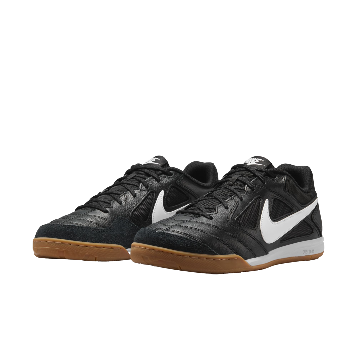 Black Nike indoor soccer shoes with white swooshes and gum outsoles, shown against a black background.