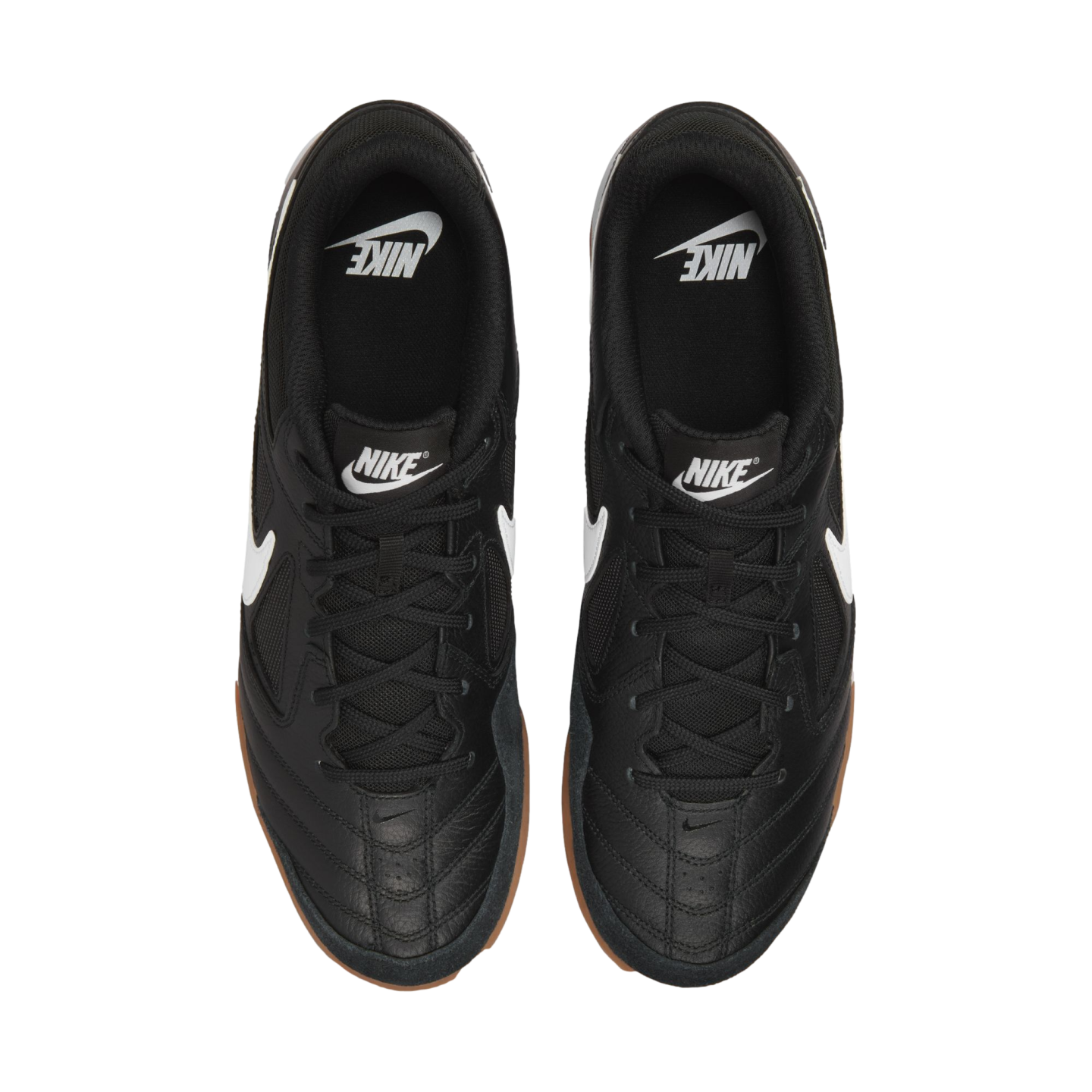 Top-down view of black Nike sneakers with white swooshes and gum rubber soles against a black background.