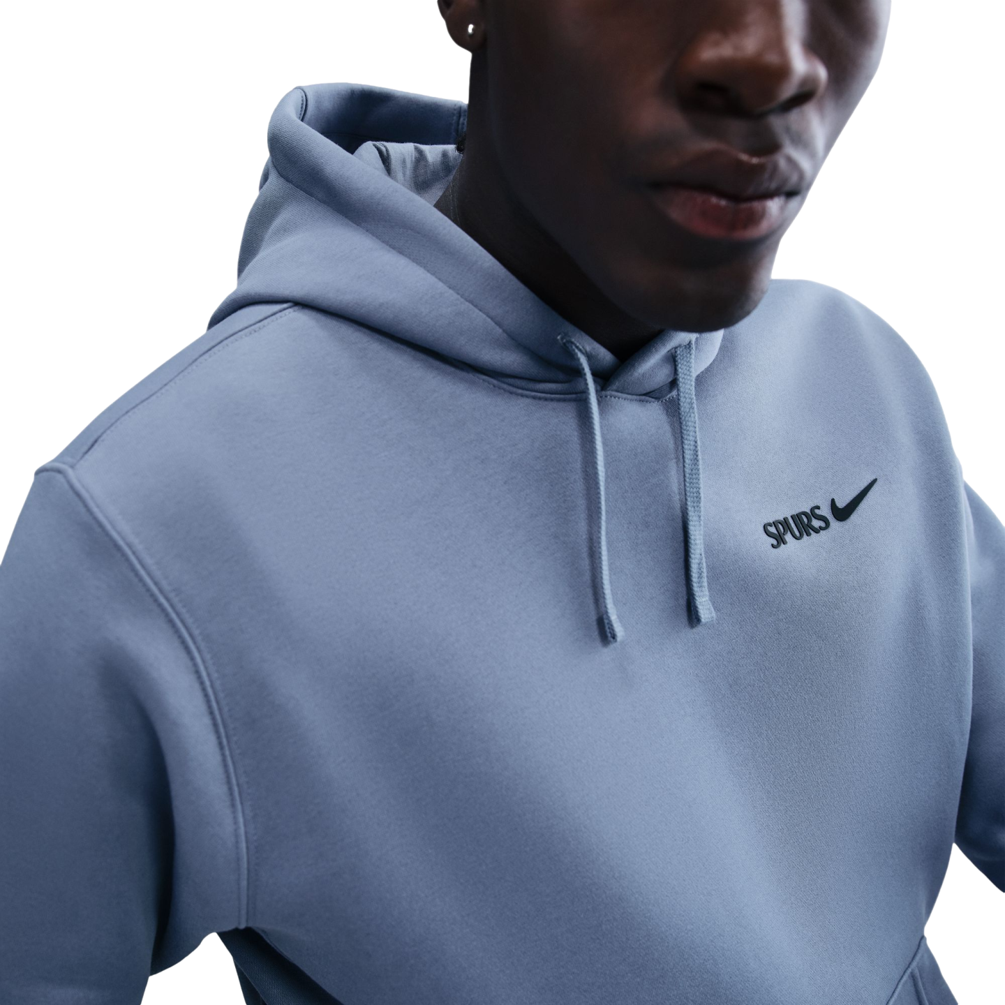 A close-up shot of a person wearing a light blue Nike hoodie with "SPURS" printed on the chest.