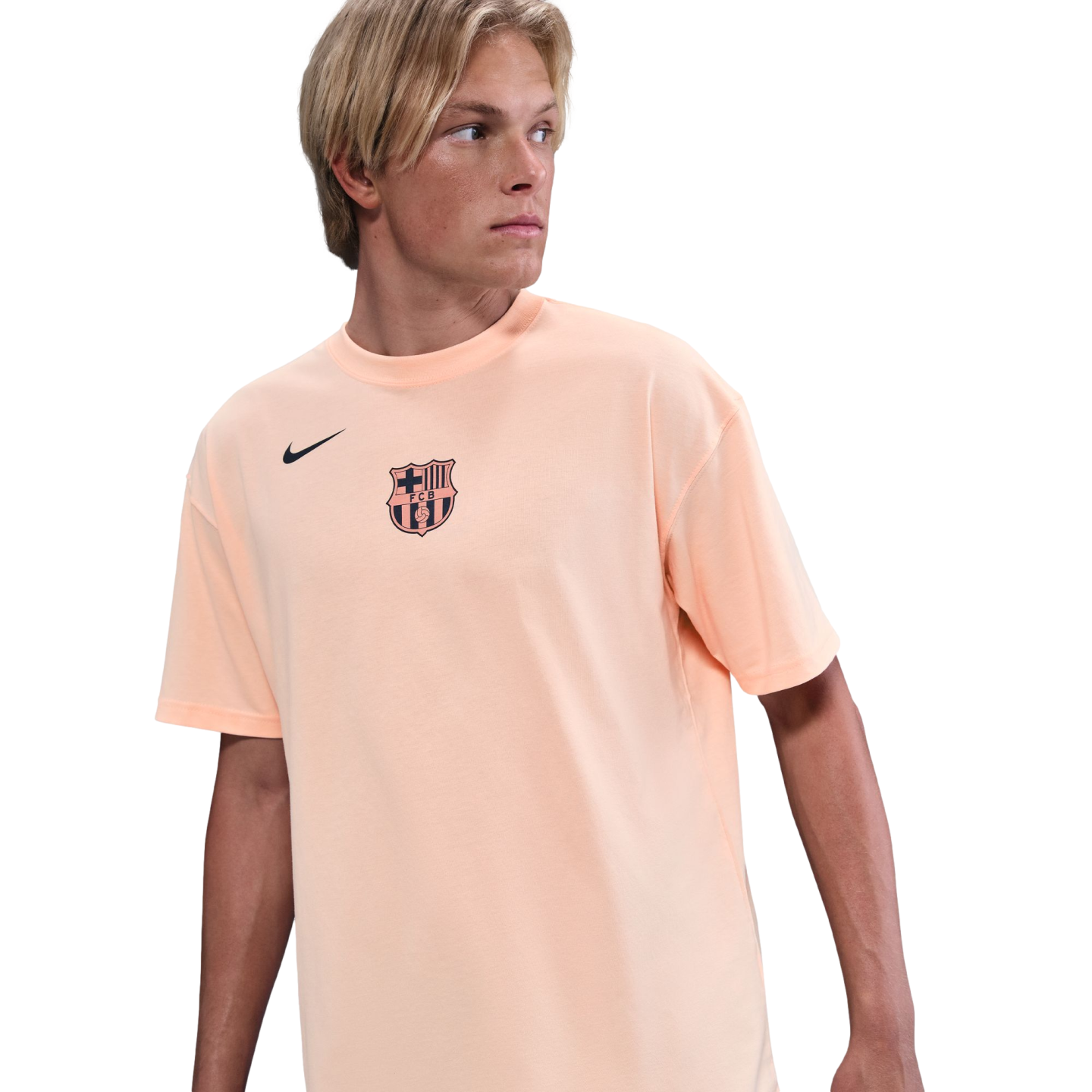 A young man with blond hair wearing a peach-colored FC Barcelona Nike t-shirt, looking to the side against a solid black background.