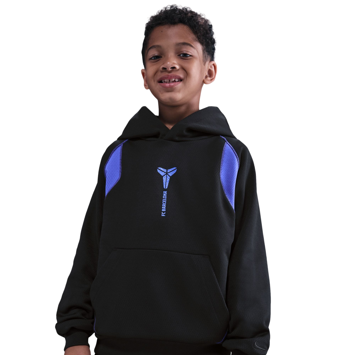 A smiling young boy with curly hair wearing a black Nike hoodie with a blue Kobe Bryant logo and "FC Barcelona" text, isolated against a solid black background.
