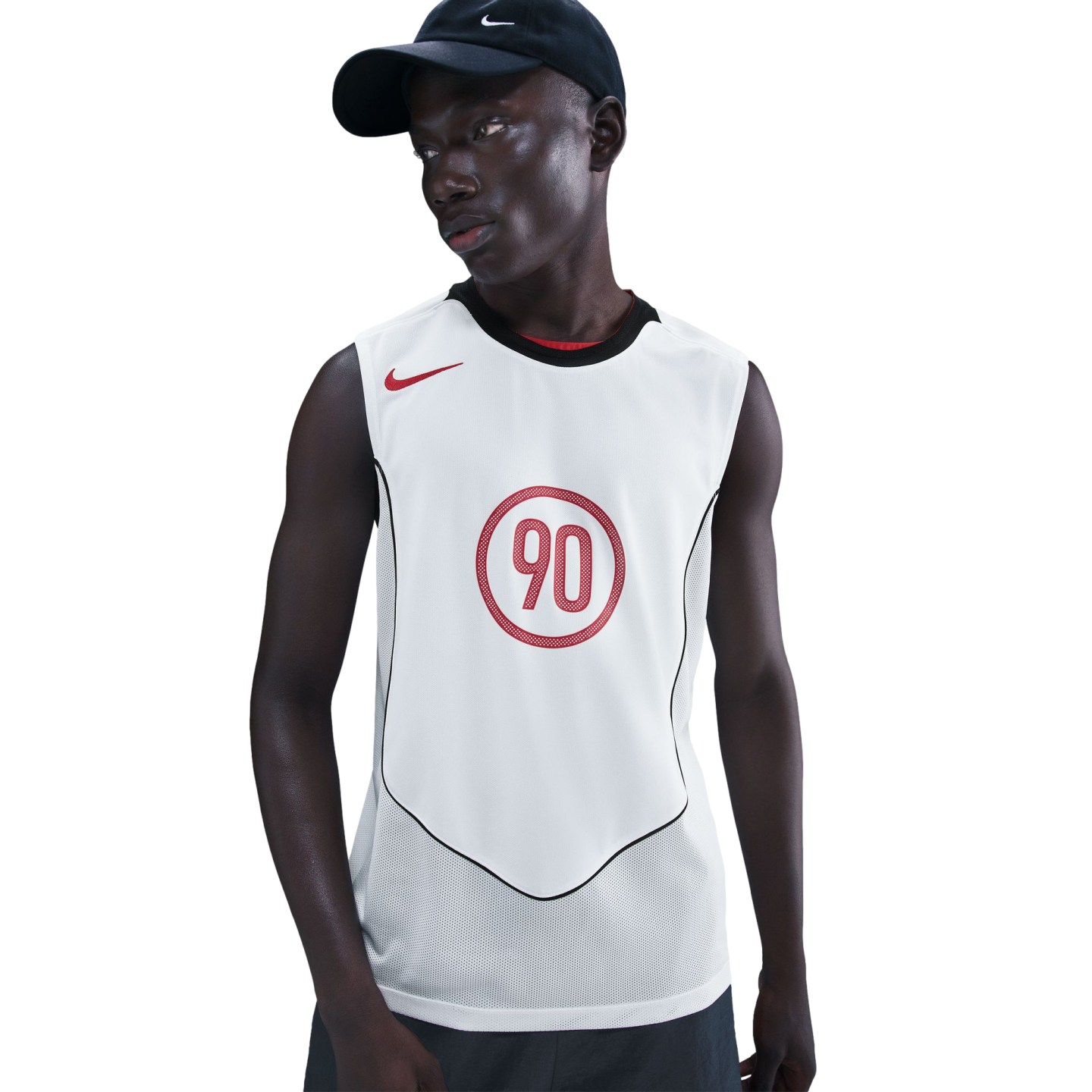 A man wearing a black Nike cap and a white sleeveless athletic top with a red Nike swoosh and a red "90" logo, posed against a solid black background.