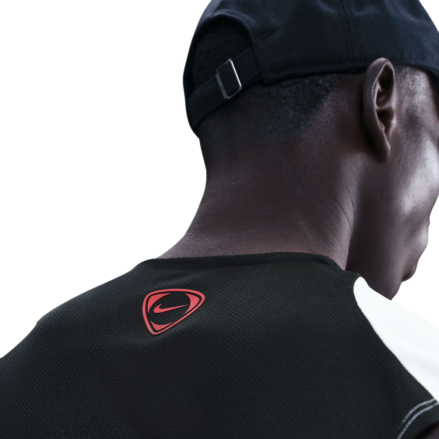 Close-up rear view of a man wearing a black baseball cap and a black athletic mesh shirt with a small red Nike logo on the back of the neck.