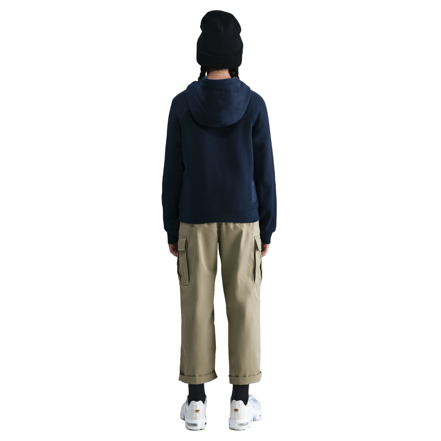 Rear view of a person wearing a black beanie, navy hoodie, tan cargo pants, and white sneakers against a black background.