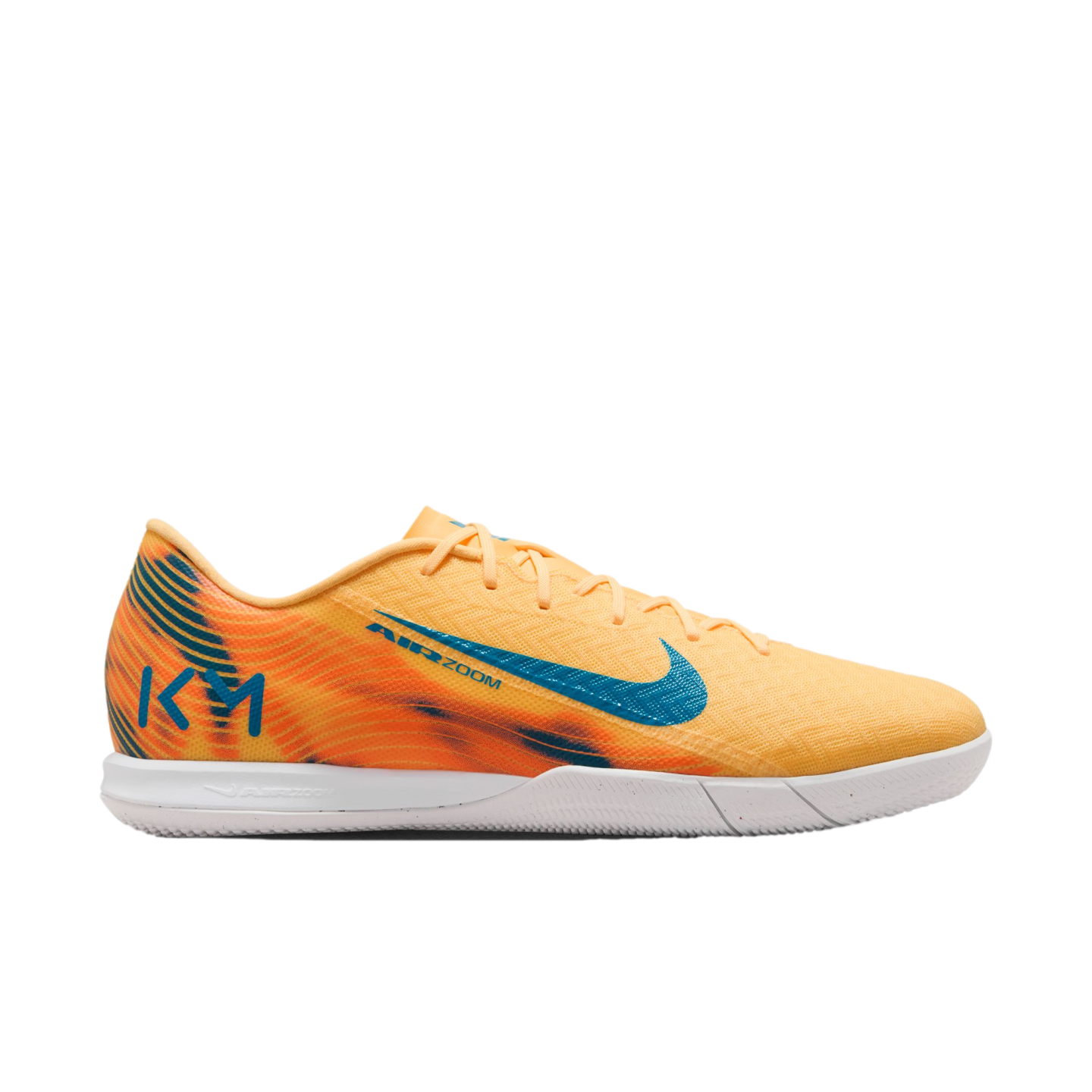 A Nike Mercurial indoor soccer shoe in light orange with blue accents and Kylian Mbappé "KM" branding on the heel, set against a black background.