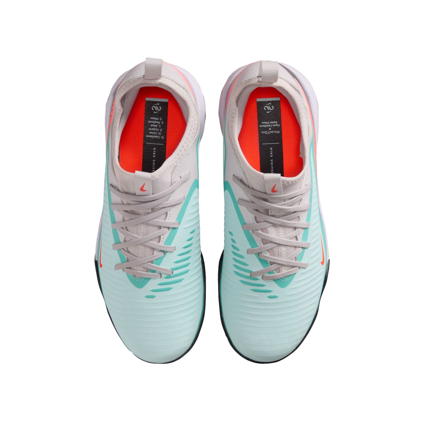 Top-down view of mint green Nike Phantom soccer shoes with grey laces and orange insoles against a black background.