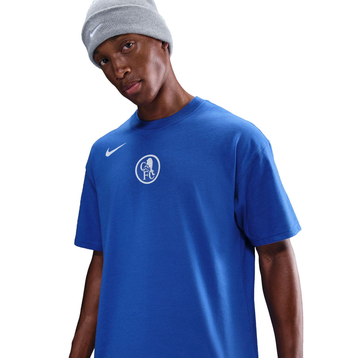 A man in a grey Nike beanie and a blue Nike Chelsea FC t-shirt with a white central crest, set against a black background.