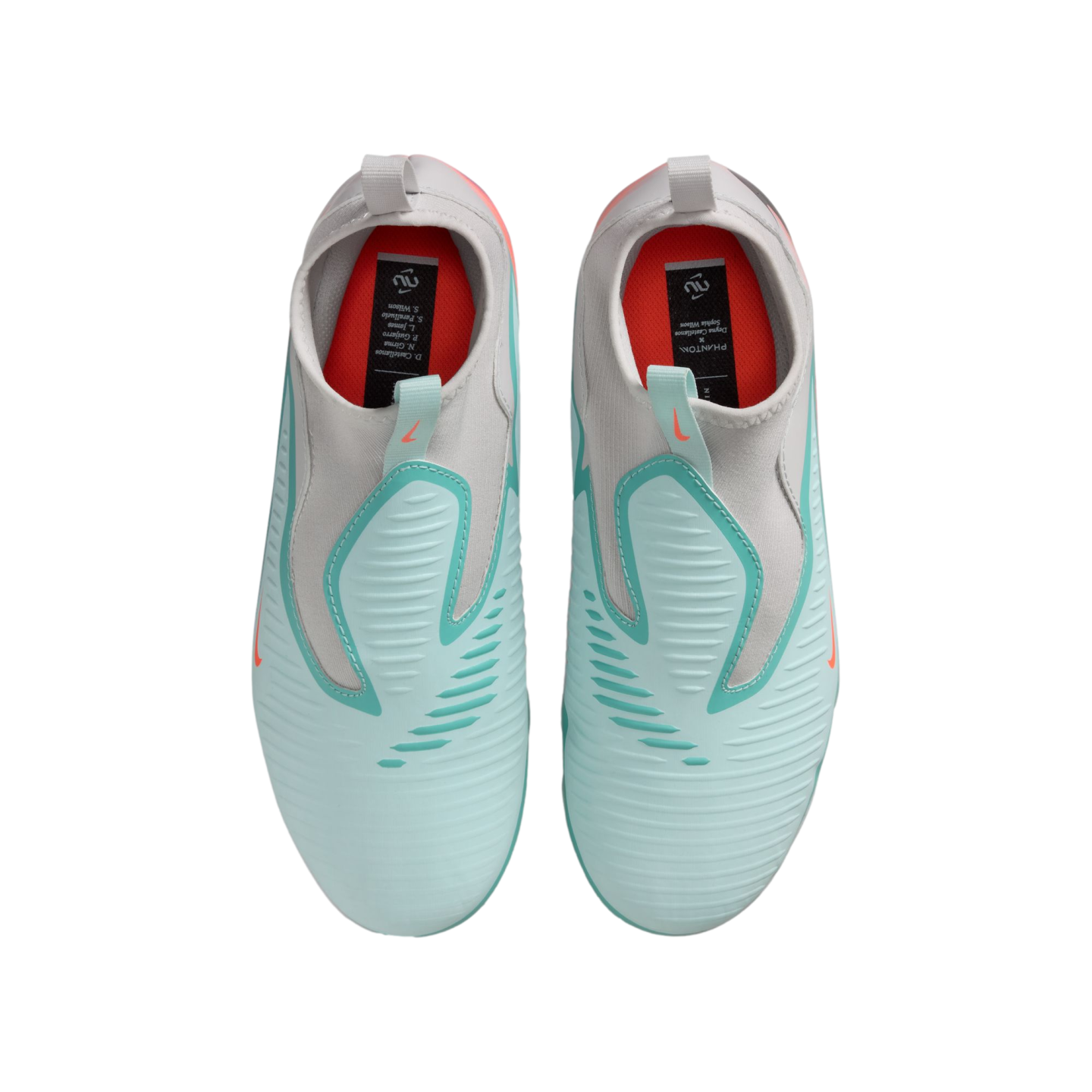 Top-down view of light blue and gray laceless Nike soccer cleats with orange accents. They feature a sock-like collar and are shown against a black background.