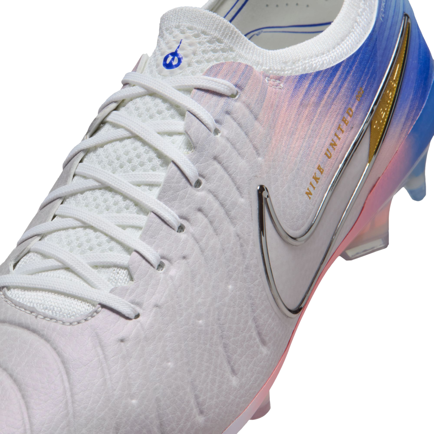 A Nike United soccer cleat with a white textured upper, chrome swoosh, and a blue and pink gradient design toward the heel.