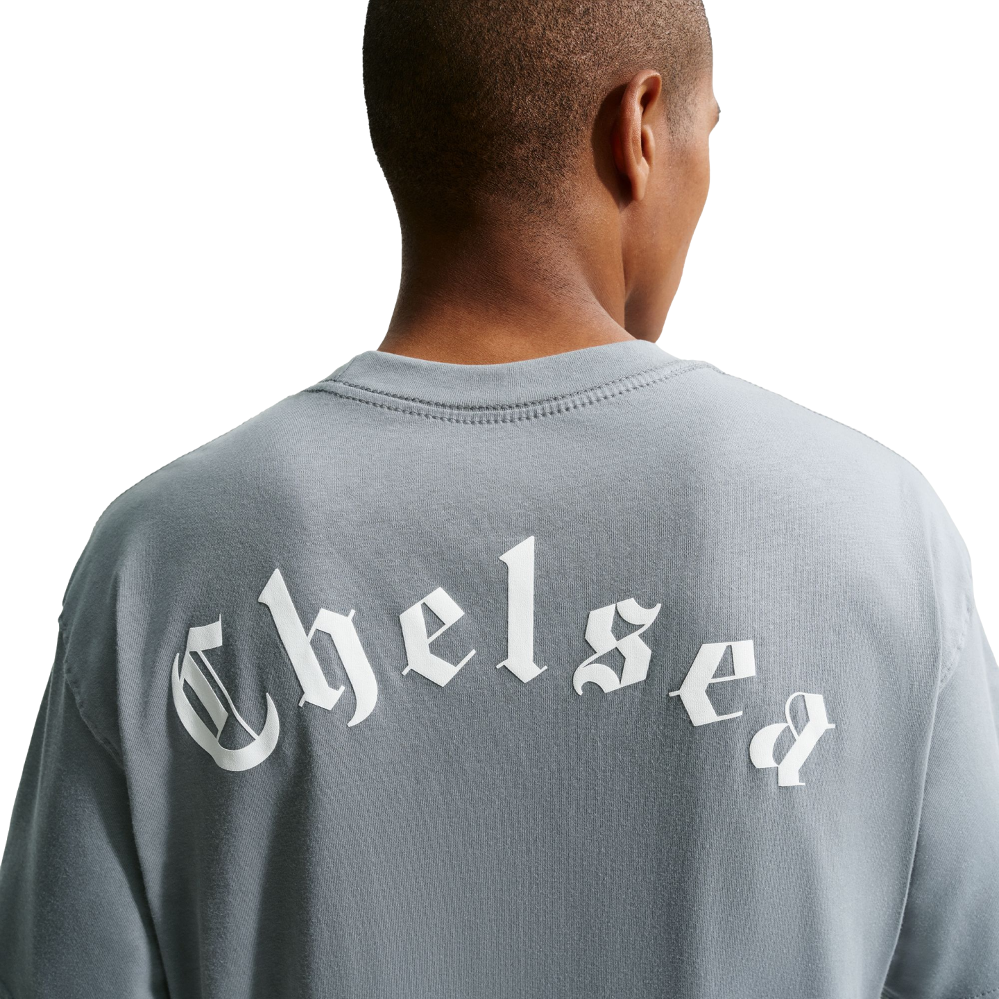 Back view of a person wearing a gray t-shirt with "Chelsea" printed in white Old English lettering across the back, set against a solid black background.