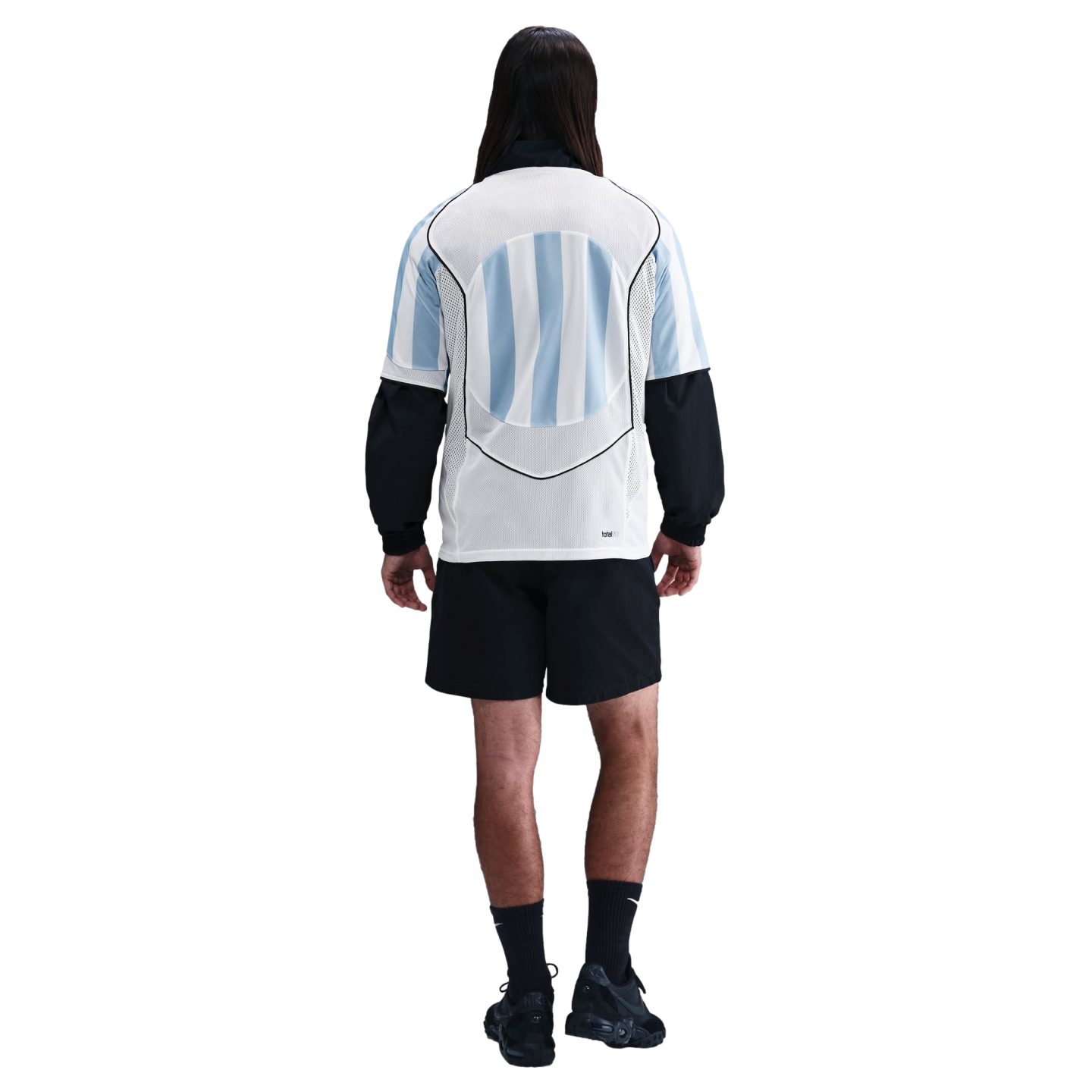 Rear view of a person with long hair in a light blue and white striped soccer jersey, black shorts, and black athletic gear against a white background.