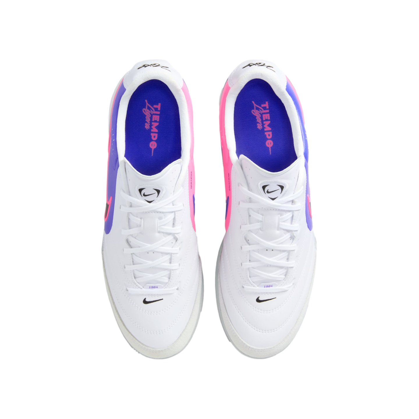 A pair of white Nike Tiempo Ligera soccer cleats with pink and purple accents, shown from a top-down perspective against a solid black background.