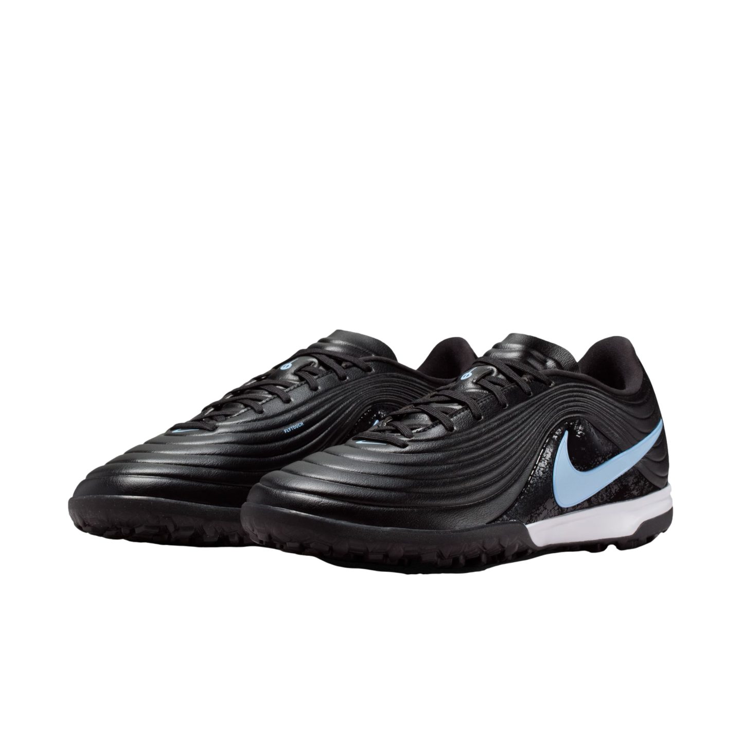 Pair of black Nike turf soccer shoes with a light blue swoosh, white midsole, and textured ridged upper on a black background.