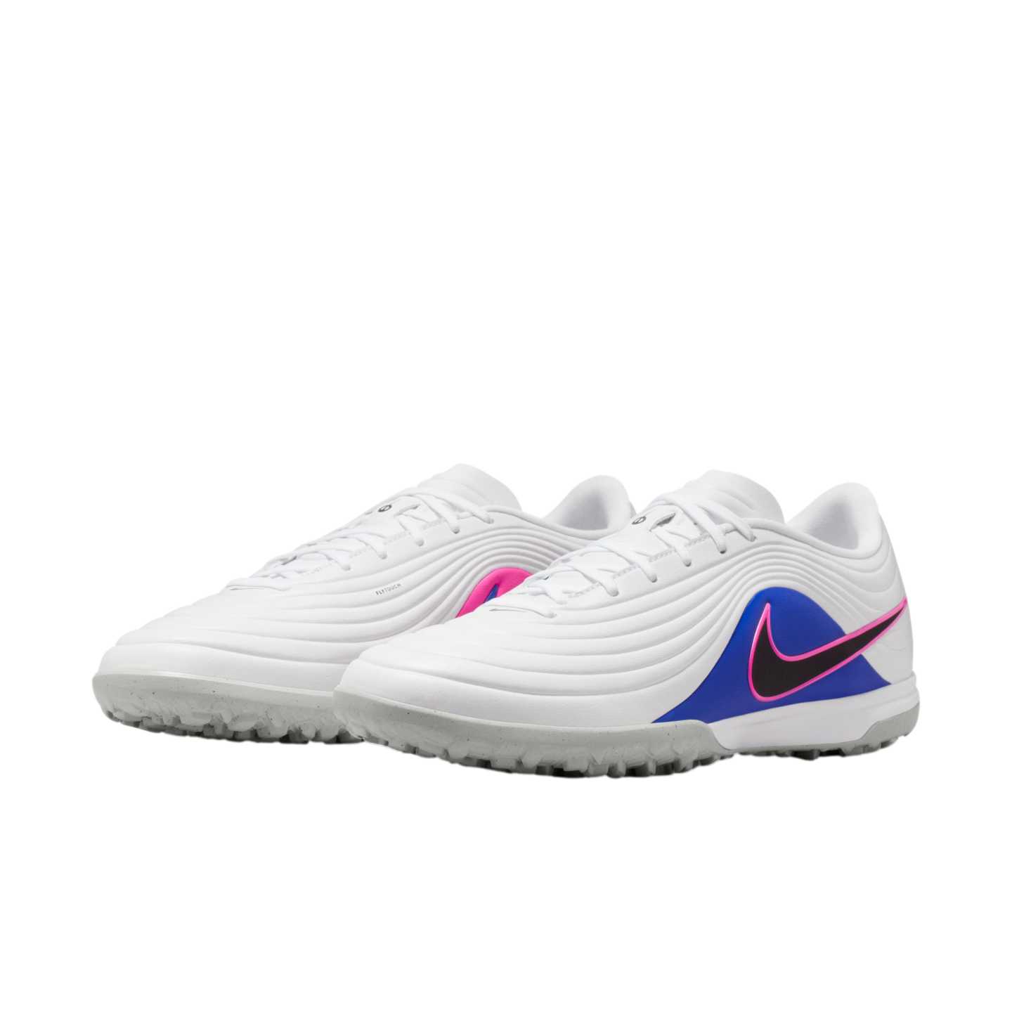 White Nike turf soccer shoes with textured uppers, a pink-outlined black swoosh on a blue heel panel, and grey studded outsoles.