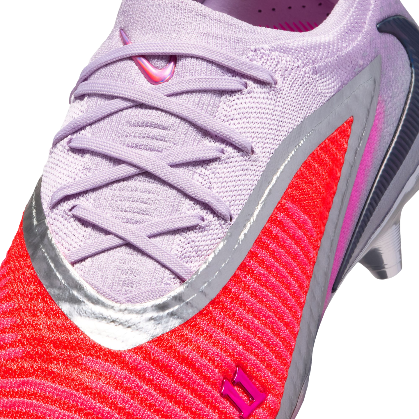 Close-up of a Nike soccer cleat with a light purple knit upper, matching laces, and a vibrant red-orange textured section outlined in silver.