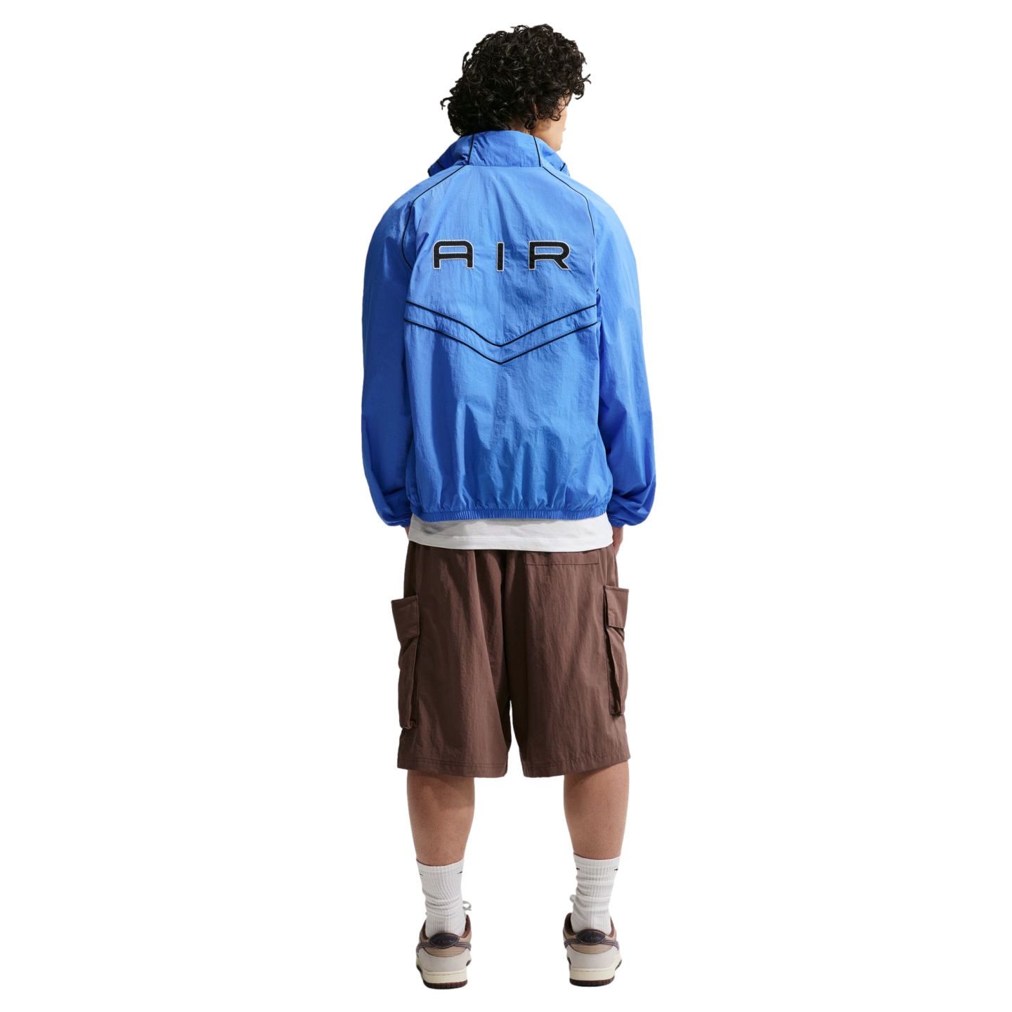 Back view of a person wearing a blue "AIR" windbreaker jacket, brown cargo shorts, and sneakers.