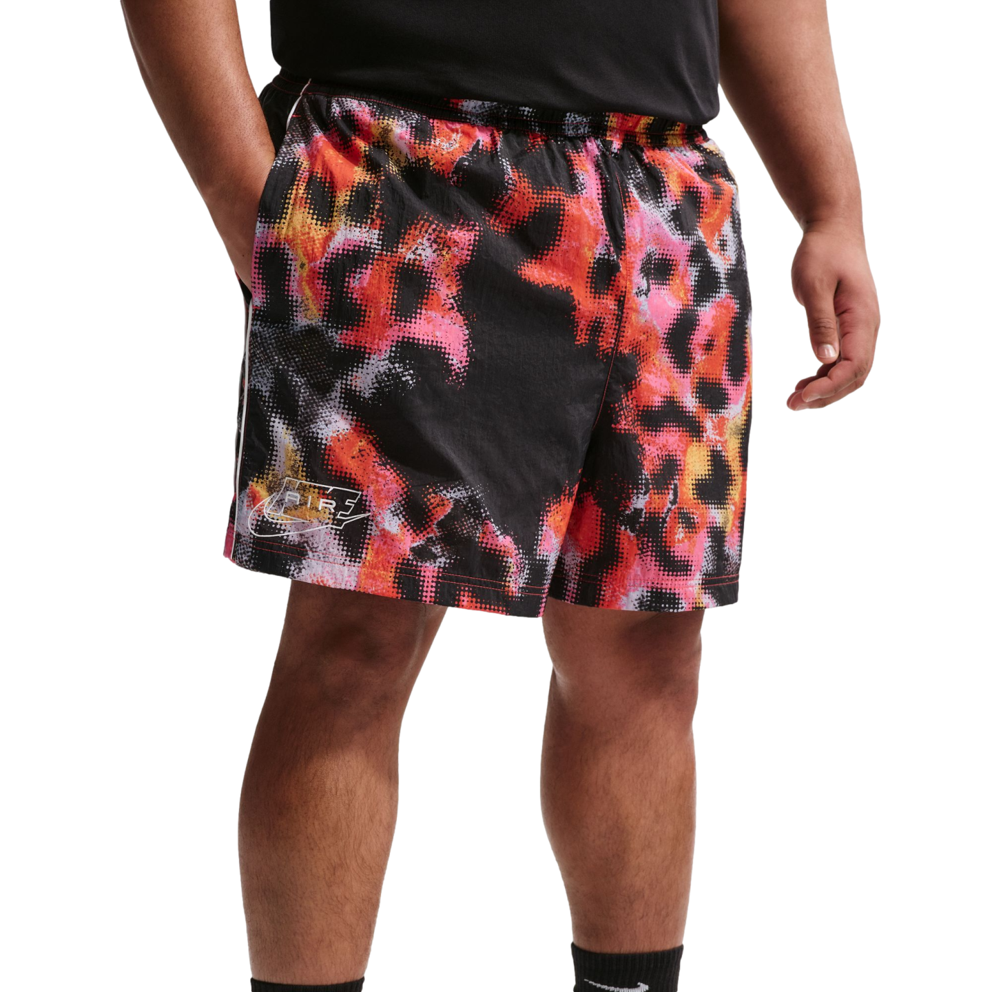 A person's mid-section wearing black Nike shorts featuring a vibrant, pixelated red, orange, and pink fire-like pattern with a small white logo.