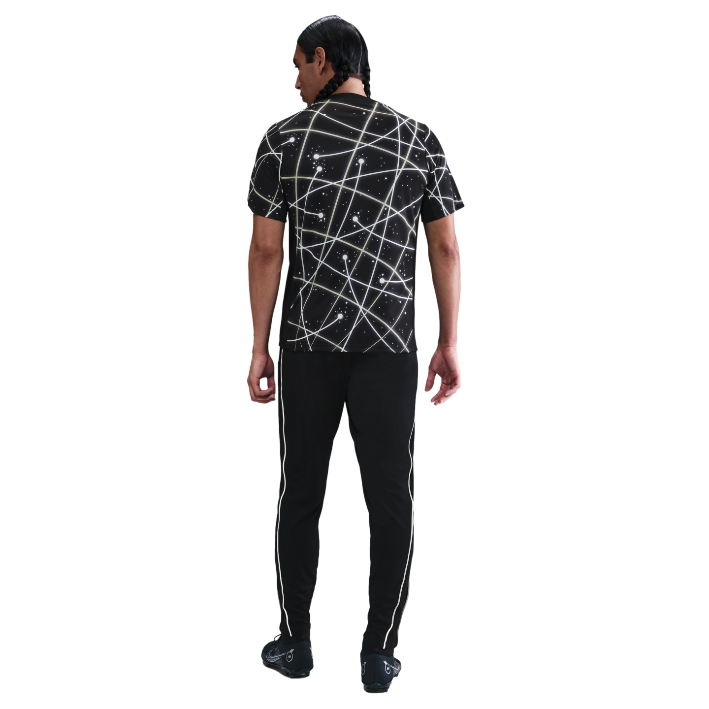 Rear view of a man with braided hair wearing a black t-shirt with white abstract line patterns and black athletic pants with white side stripes.
