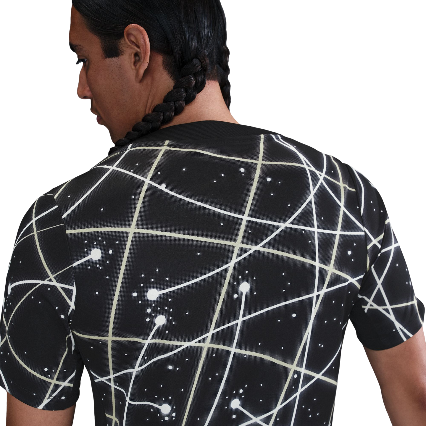 Back view of a person with long braids wearing a black t-shirt featuring a white geometric constellation pattern, set against a white background.