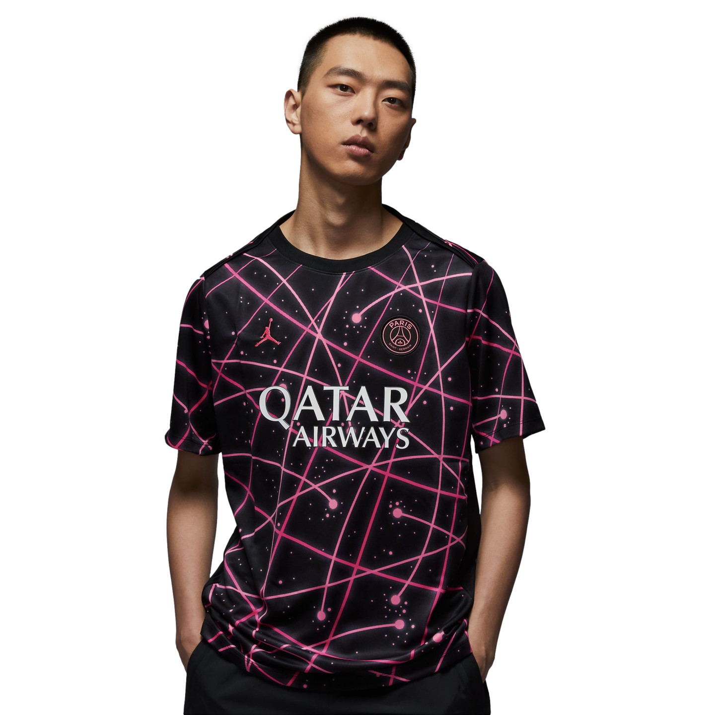 Man modeling a black Paris Saint-Germain jersey featuring pink intersecting lines and a white Qatar Airways logo against a white background.