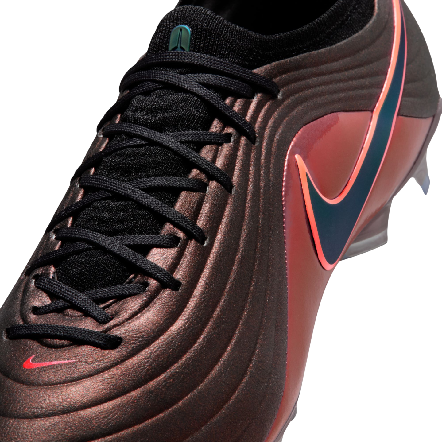 Close-up of a textured bronze Nike soccer cleat with black laces and an iridescent blue swoosh outlined in pink.