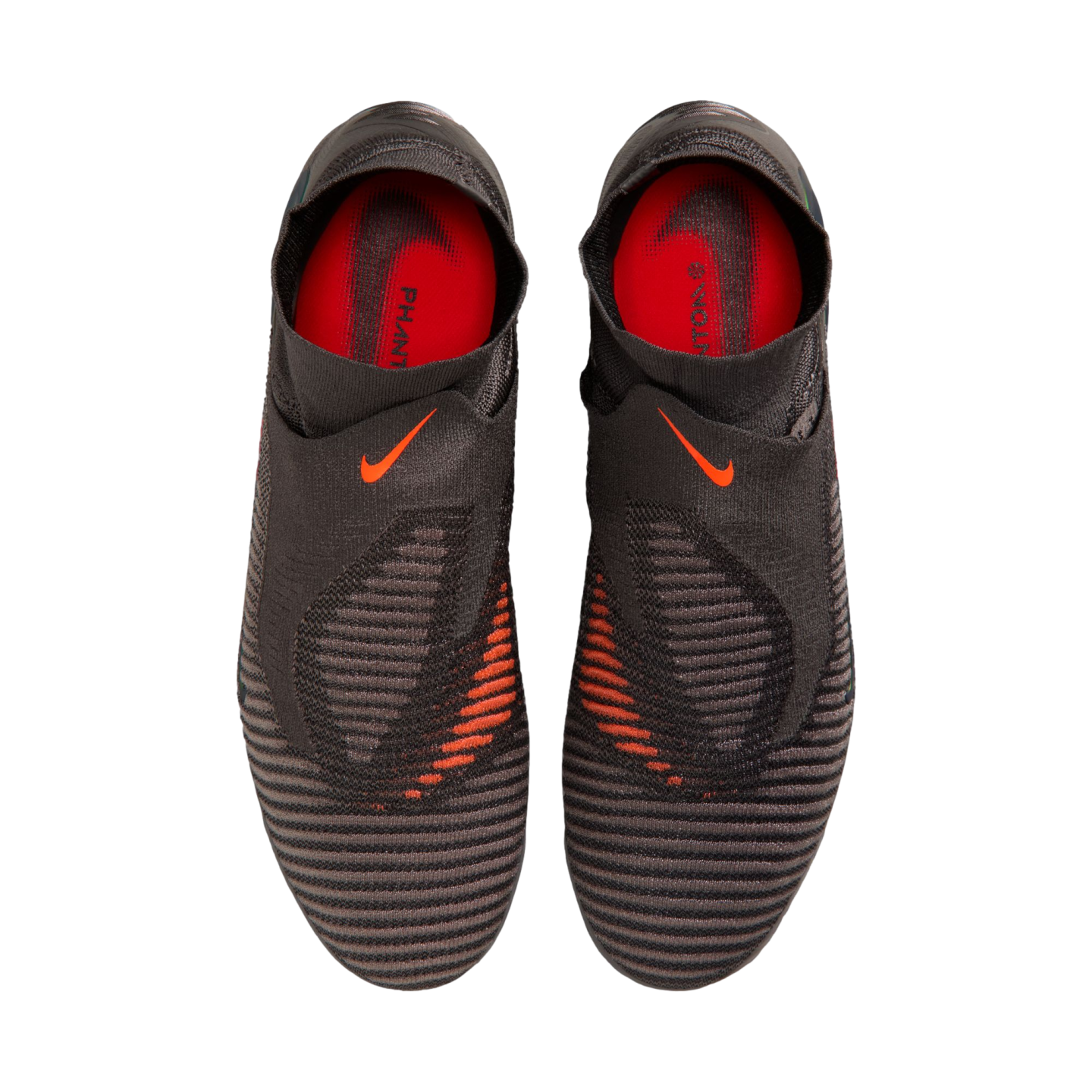 A top-down view of a pair of black Nike Phantom laceless soccer cleats with bright orange accents and a textured upper against a black background.