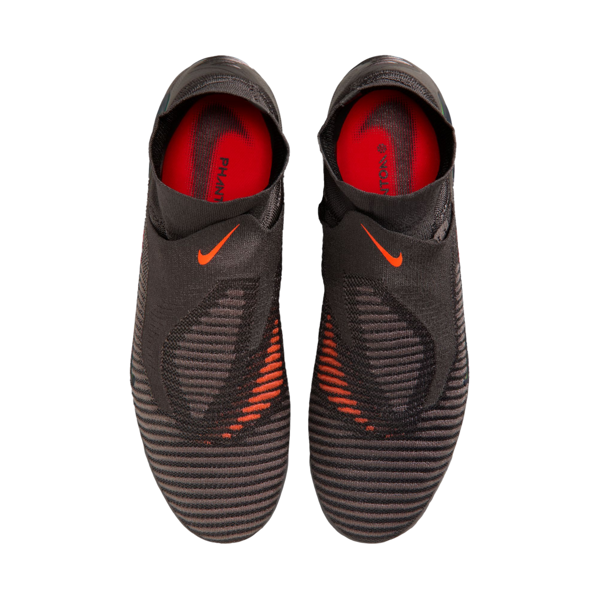 A top-down view of a pair of black Nike Phantom laceless soccer cleats with bright orange accents and a textured upper against a black background.