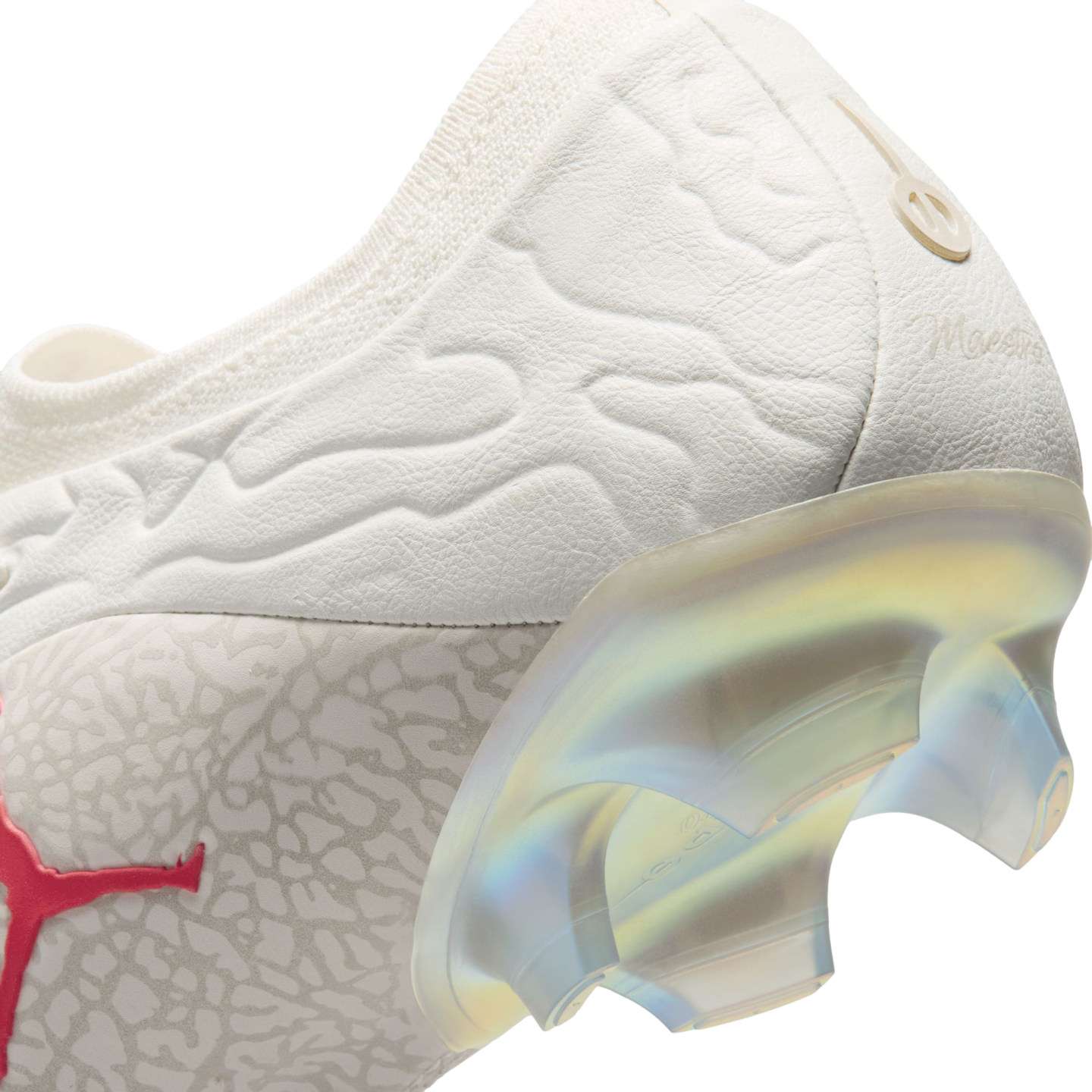 Close-up of a white Puma soccer cleat heel with a textured upper, a red Puma logo, and a semi-translucent iridescent soleplate with studs.