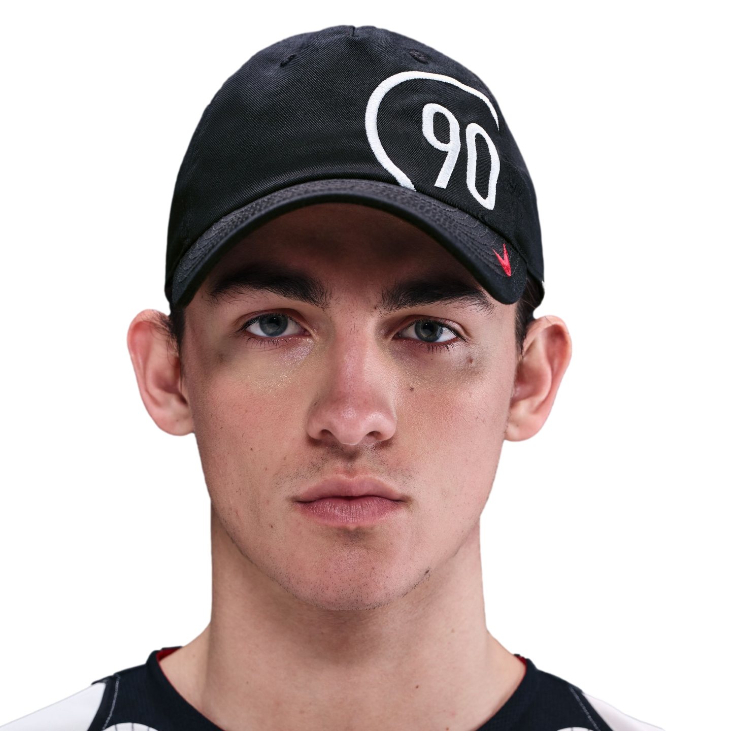 Headshot of a young man with light eyes and prominent dark circles under them, wearing a black baseball cap with a white "90" logo.