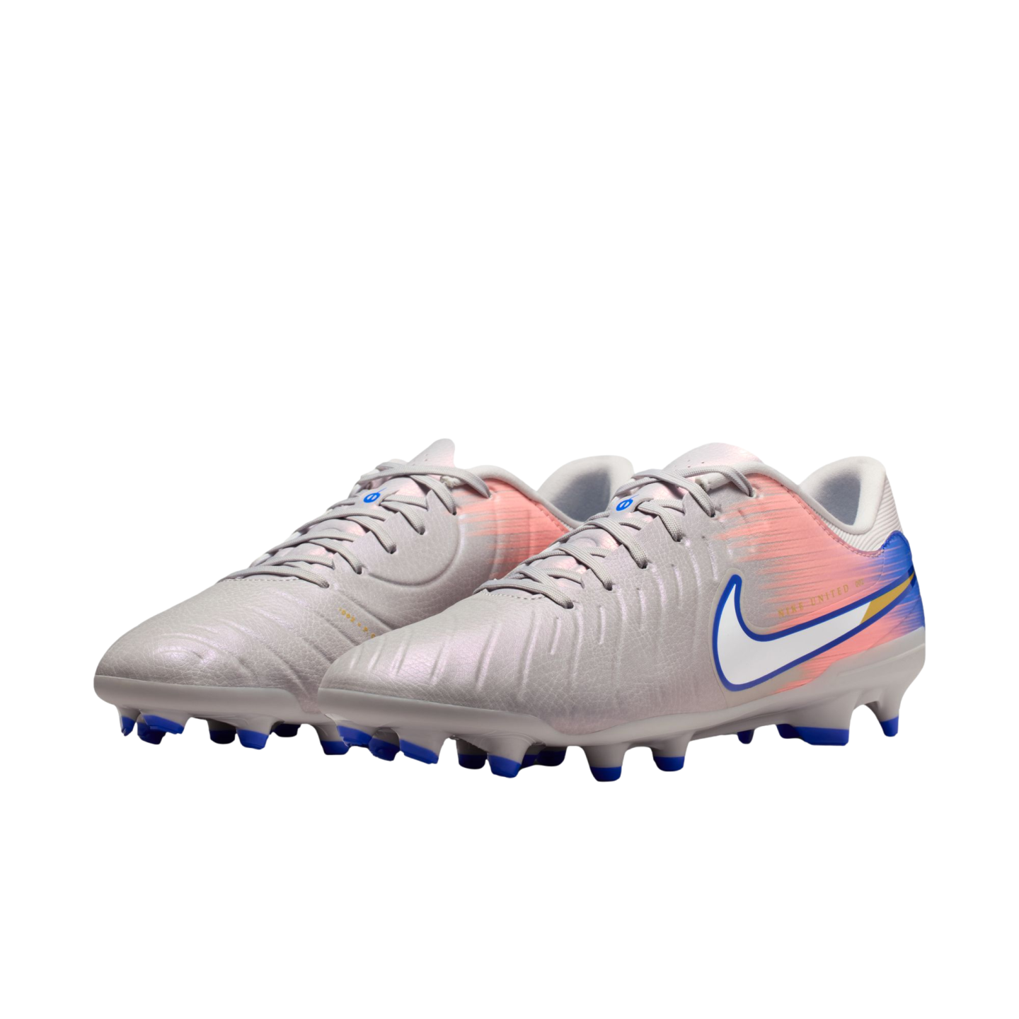 Light grey Nike soccer cleats with a pink and blue gradient heel, white swoosh, and blue studs on a black background.