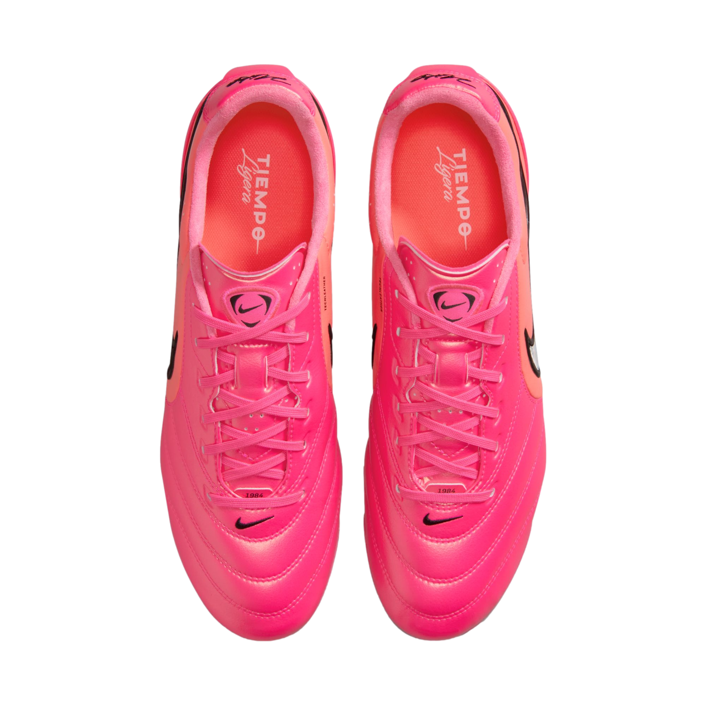 Top-down view of a pair of vibrant pink Nike Tiempo Ligera soccer shoes with pink laces and black Nike swoosh logos on a white background.