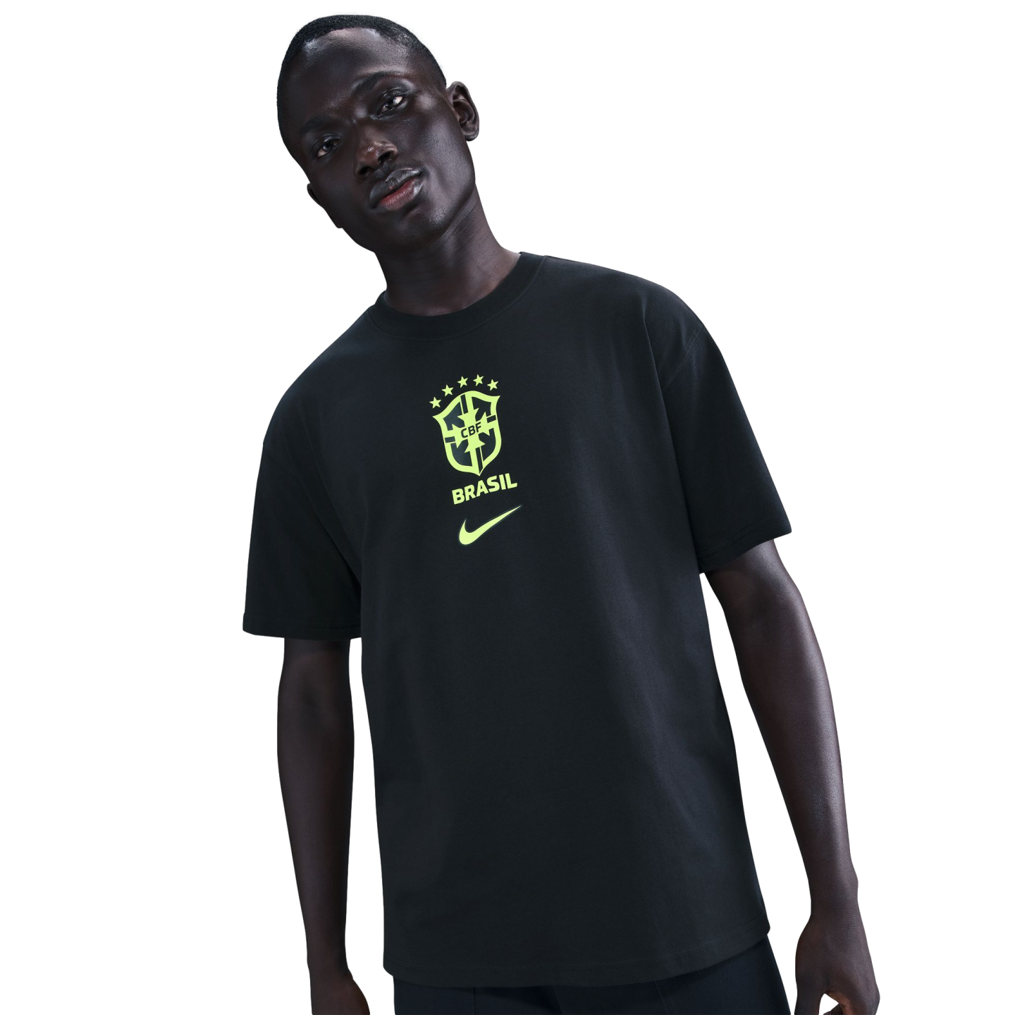 A man wearing a black t-shirt with a neon green Brazil football crest and Nike logo, against a solid black background.