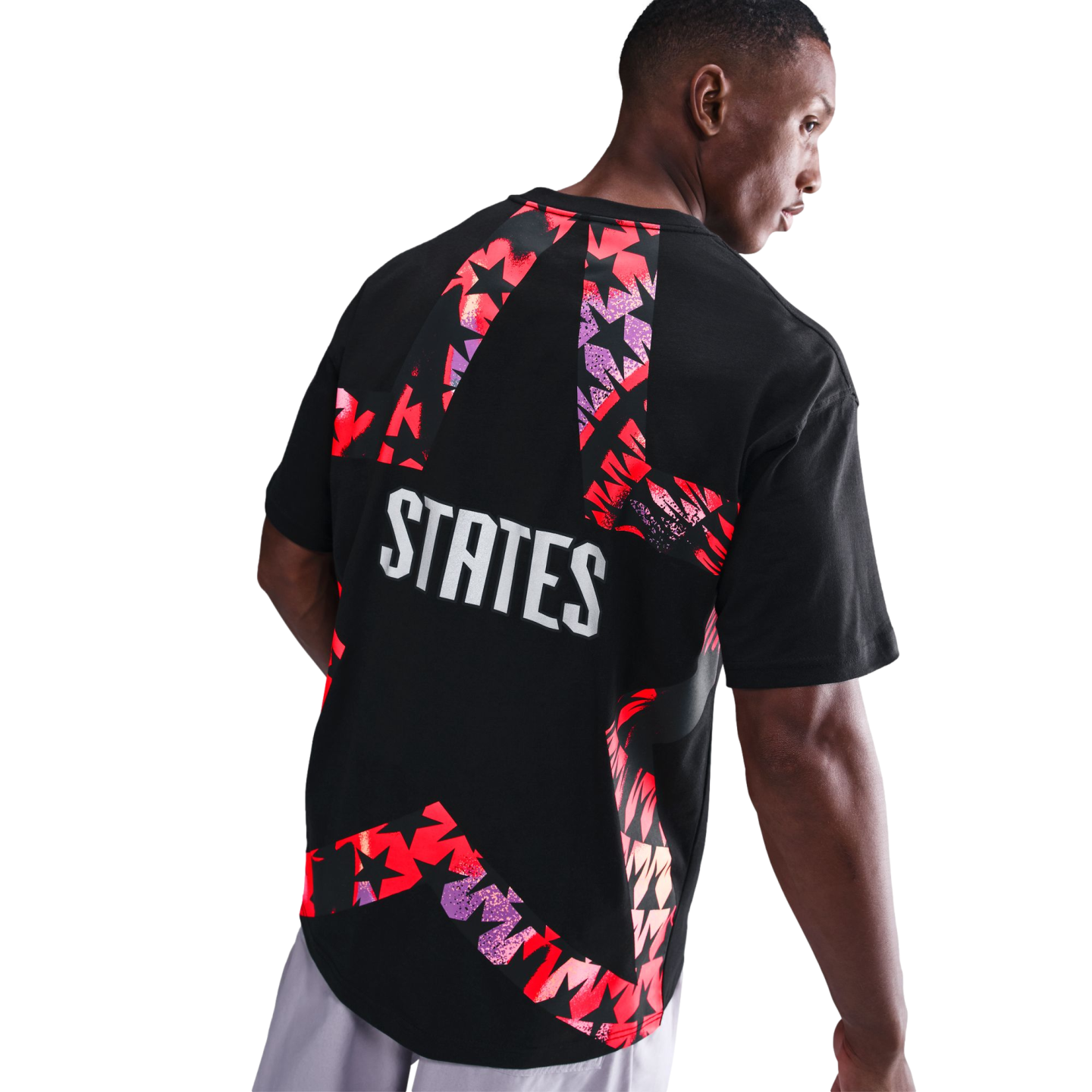 Rear view of a man wearing a black t-shirt with a large, colorful star-shaped graphic and the word "STATES" printed in bold white letters.