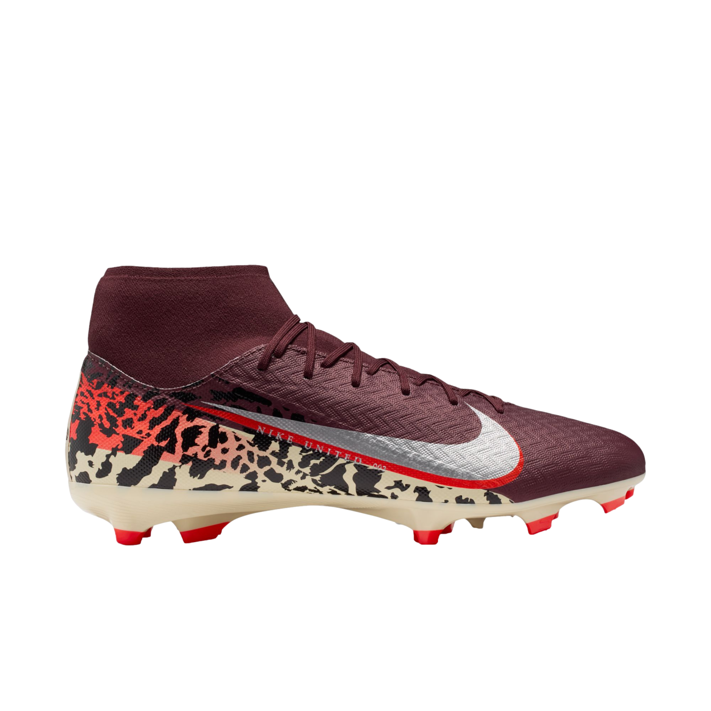 A profile view of a maroon Nike Mercurial soccer cleat against a black background. The shoe features a sock-like ankle collar, silver Swoosh with a red outline, and a cream-colored soleplate with orange studs. A bold graphic pattern in black, orange, and