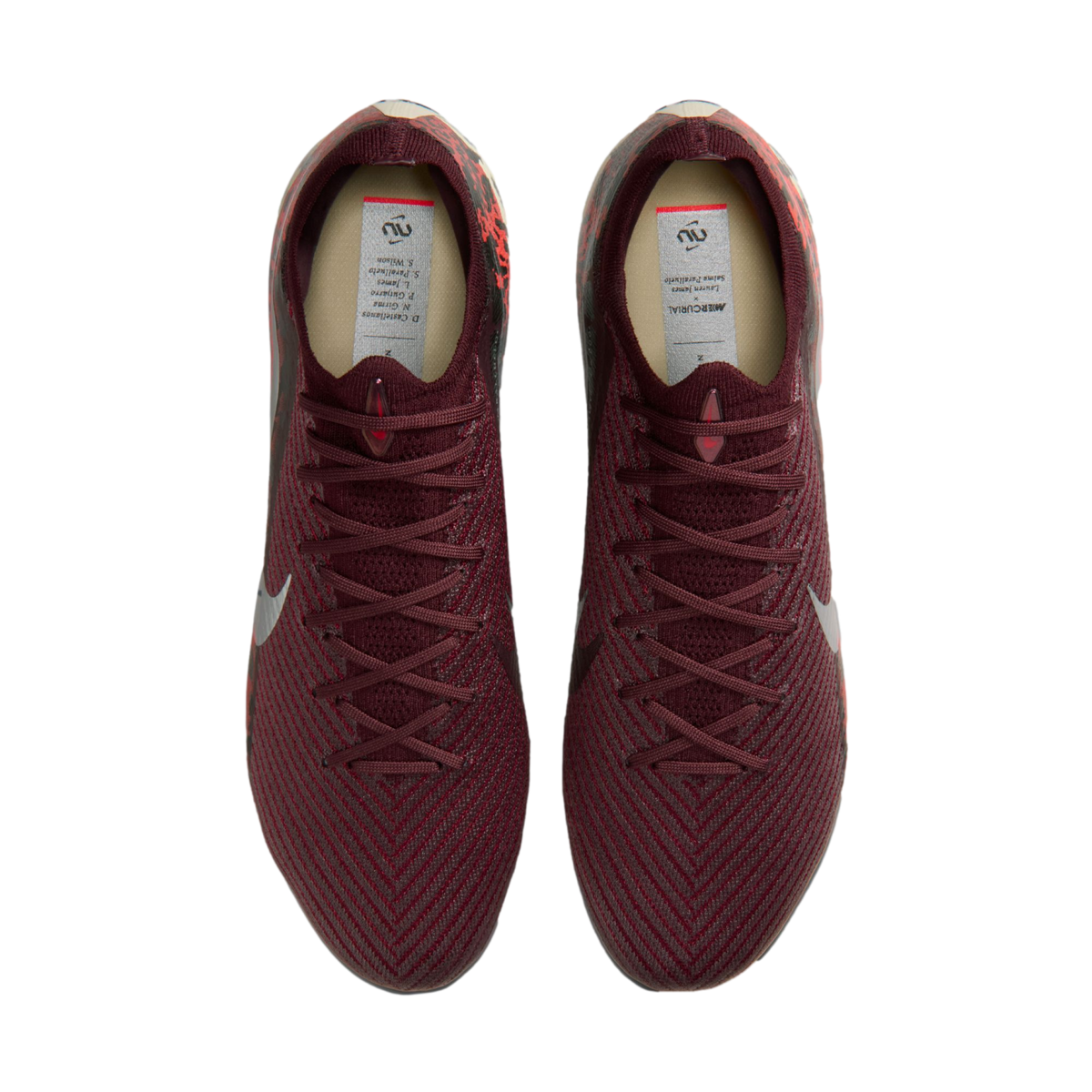 A top-down view of a pair of maroon Nike soccer cleats with a textured, knitted upper against a solid black background.