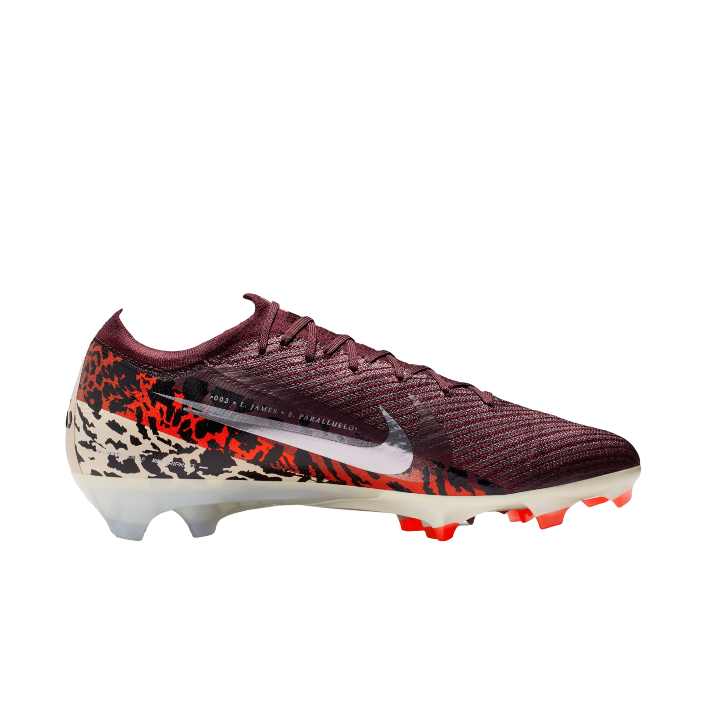 A side-profile studio shot of a Nike Mercurial soccer cleat against a solid black background. The shoe features a deep maroon ribbed upper and a large white Nike swoosh. The lower half of the boot is adorned with a bold graphic pattern in orange, black, a