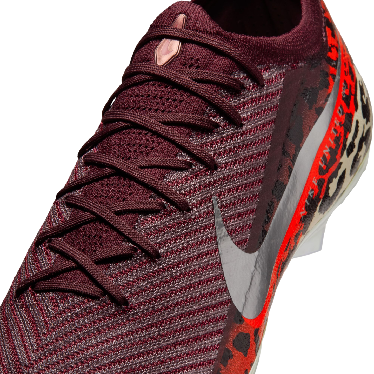A close-up, angled view of a burgundy knit Nike soccer cleat with matching laces. It features a large metallic silver Nike swoosh on the side and a vibrant orange and black leopard print pattern on the heel.
