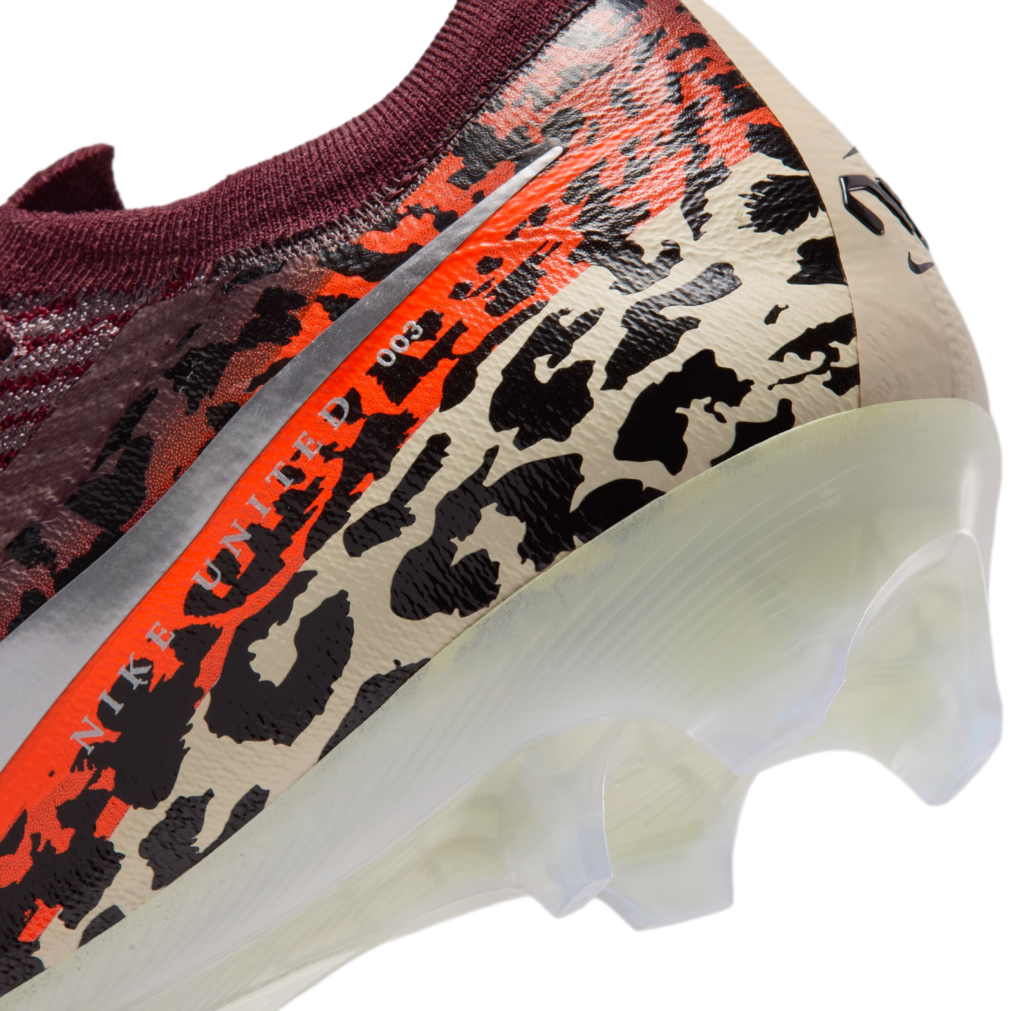 A close-up view of the heel of a Nike soccer cleat featuring a vibrant leopard print in black, orange, and beige. The text "NIKE UNITED 003" is visible along a silver stripe, and the shoe has a translucent white soleplate with clear studs.
