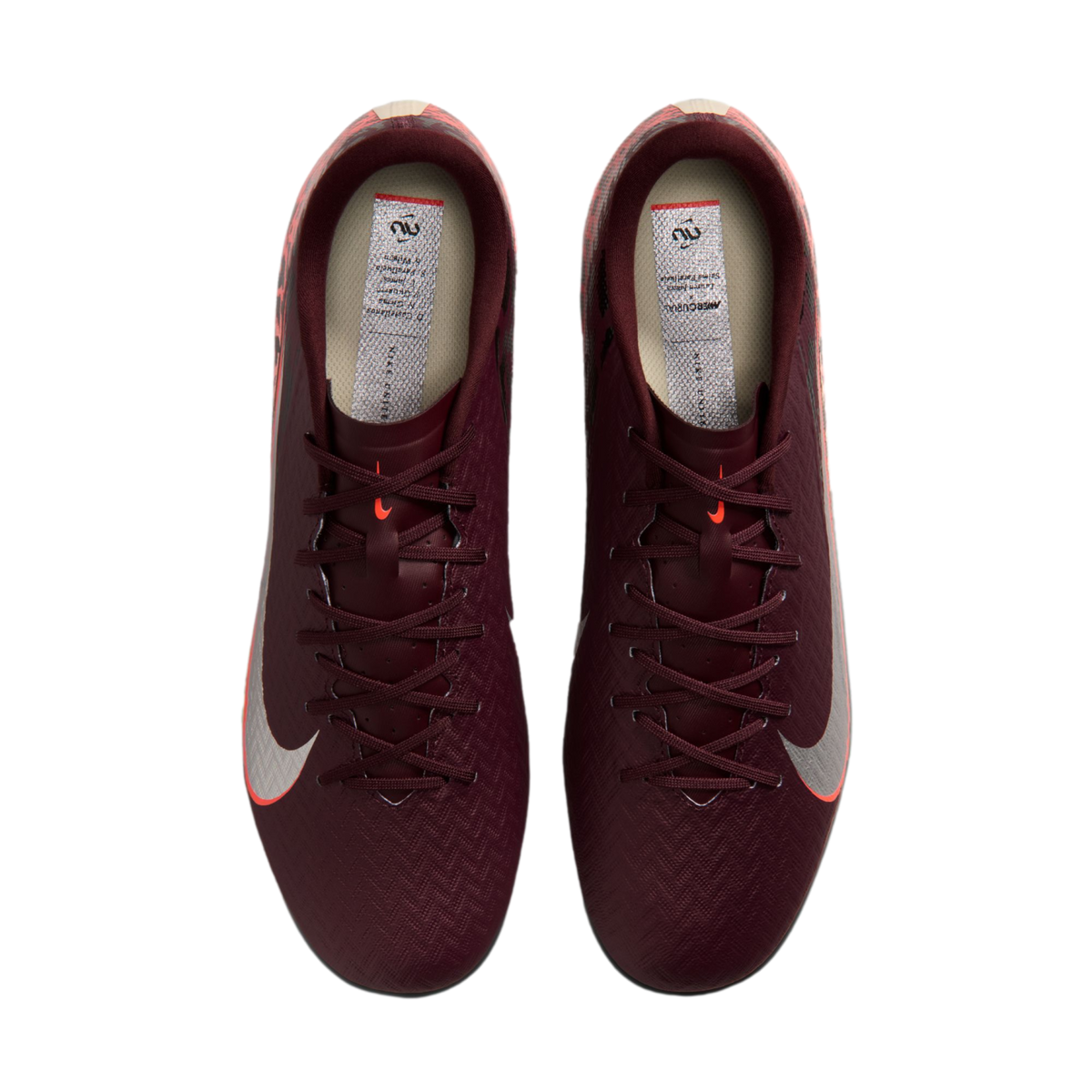 A top-down view of a pair of burgundy Nike Mercurial soccer cleats with silver Nike swooshes and orange accents, set against a black background.
