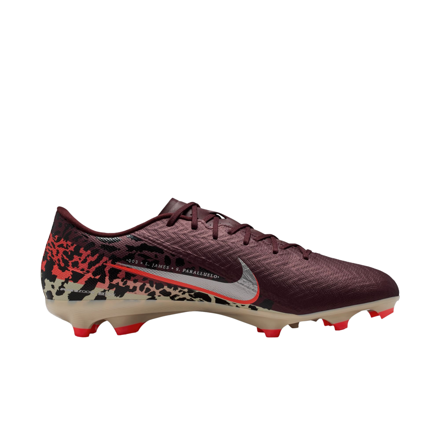 A side profile of a Nike soccer cleat against a solid black background. The shoe features a dark maroon textured upper, a silver Nike swoosh with a red outline, and a tan soleplate with bright red studs. A graphic pattern in red, black, and tan covers the